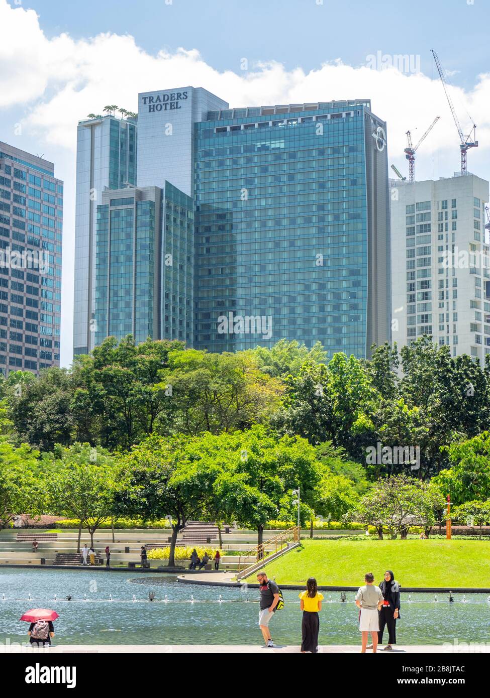 Office and residential high rise towers and fountains in Symphony Lake and tourists enjoying a day at KLCC Park Kuala Lumpur Malaysia. Stock Photo