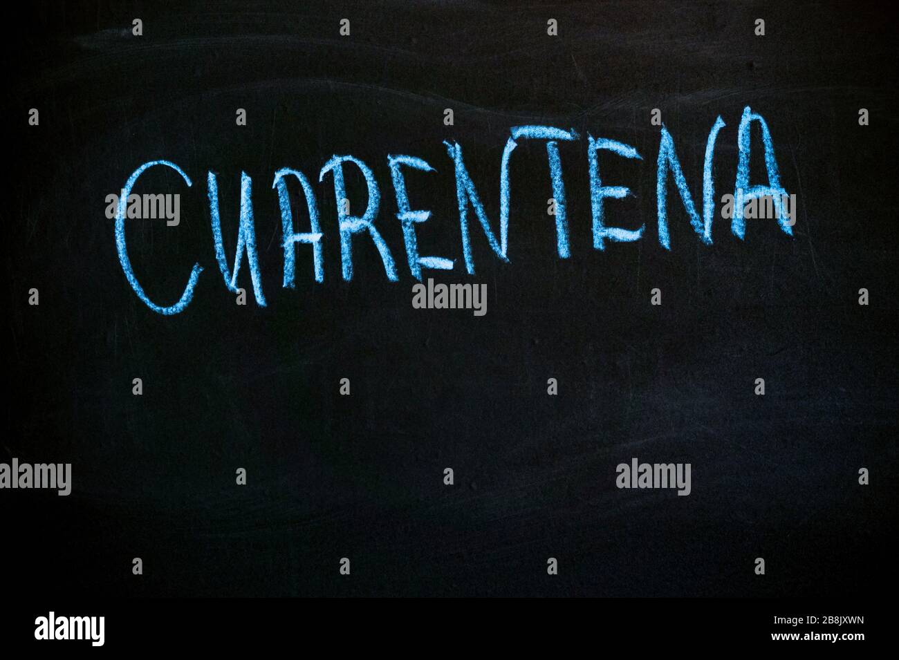 word quarantine in Spanish on a black board. Blue chalk Stock Photo Alamy