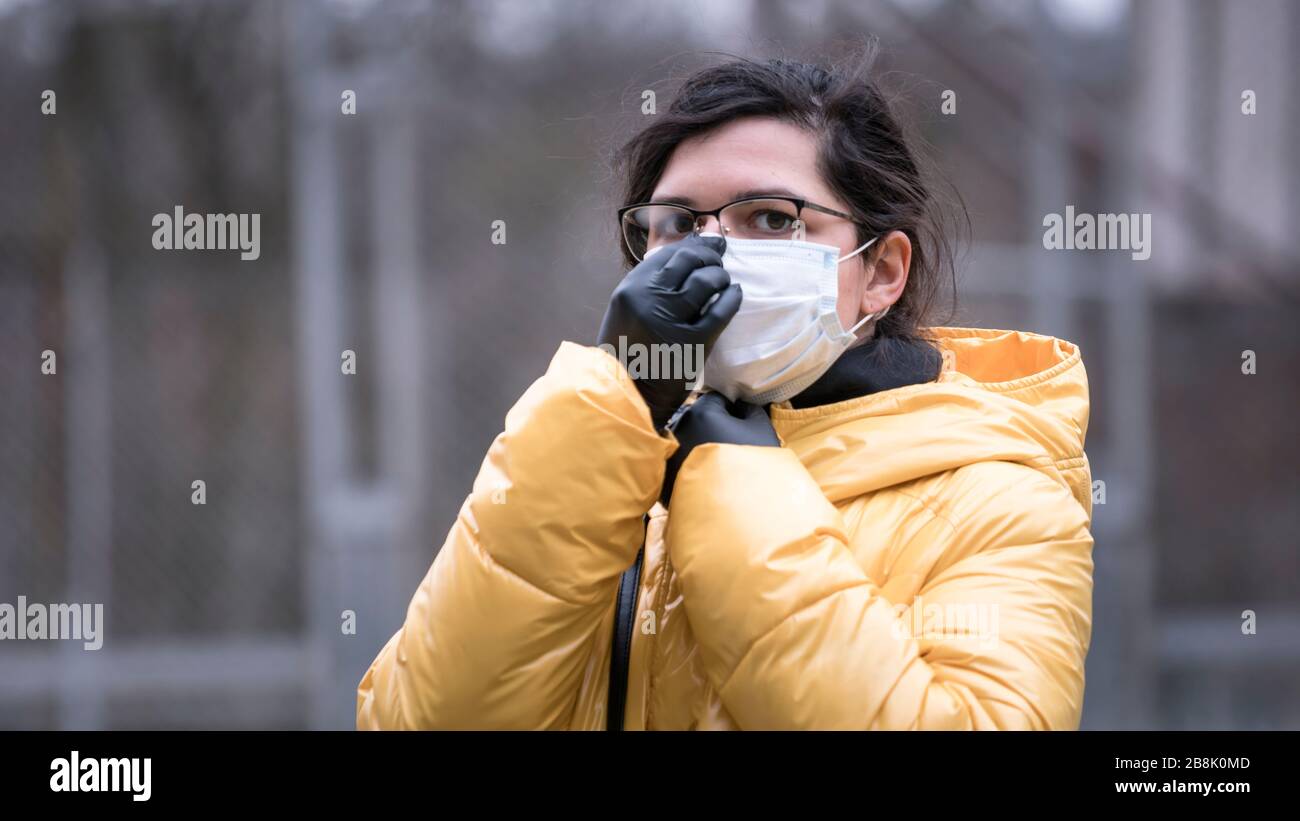 Close-up portrait young europeans woman in protective disposable medical face mask walking outdoors. New coronavirus (COVID-19). Concept of health car Stock Photo