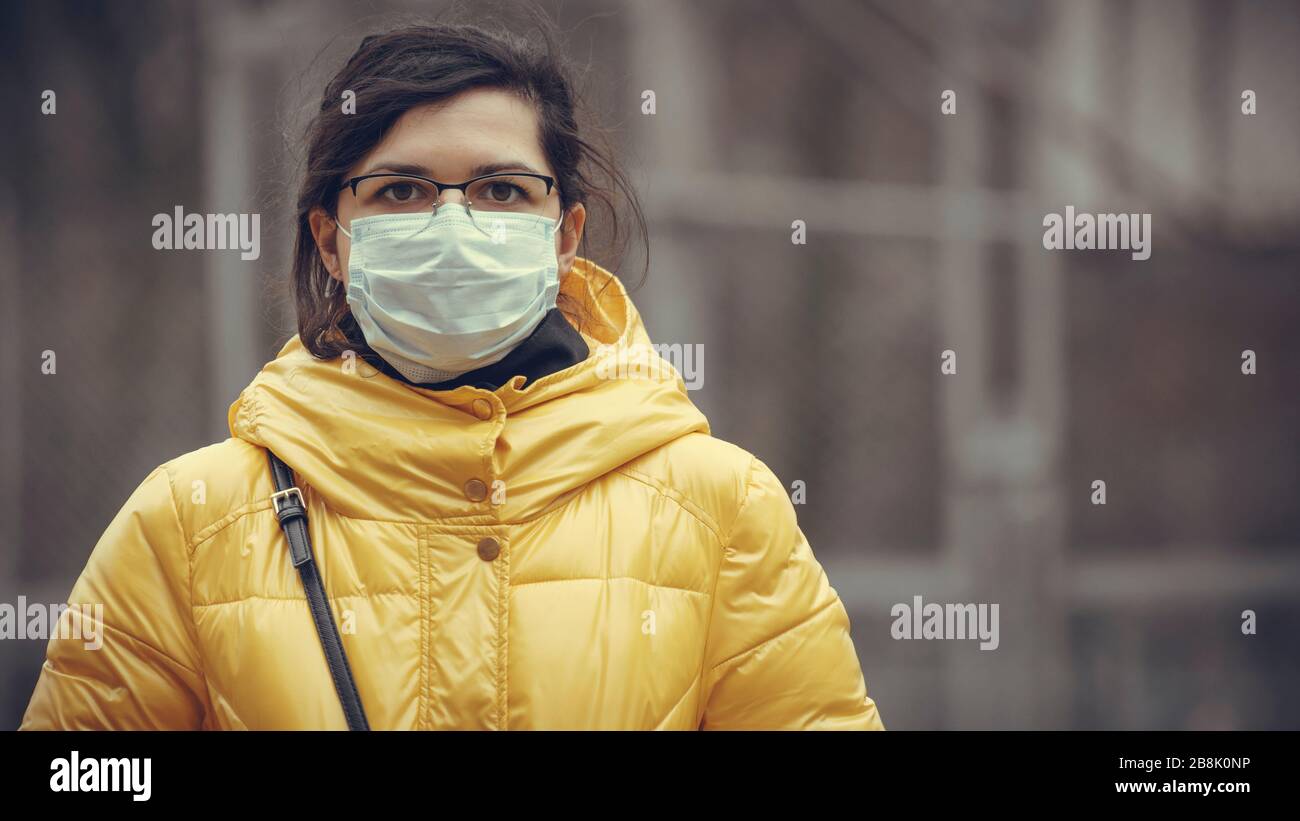 Close-up portrait young europeans woman in protective disposable medical face mask walking outdoors. New coronavirus (COVID-19). Concept of health car Stock Photo