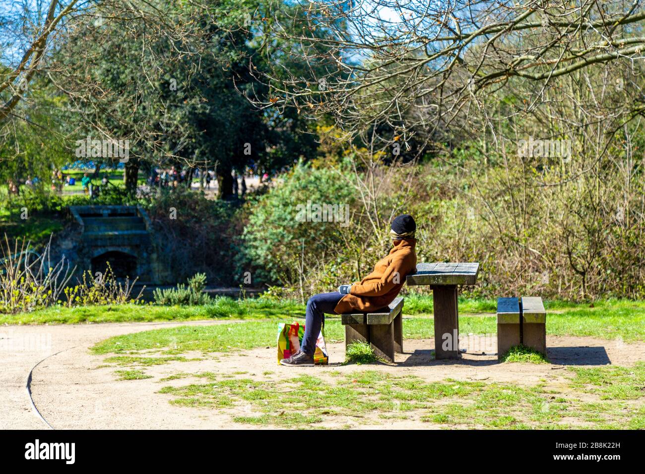 22 March 2020 - London, UK - global coronavirus pandemic, big groups of people visiting Victoria Park despite government urging people to stay at home and practice social distancing to prevent the spread of the coronavirus Covid-19, person with covering face with scarf practicing social distancing Stock Photo