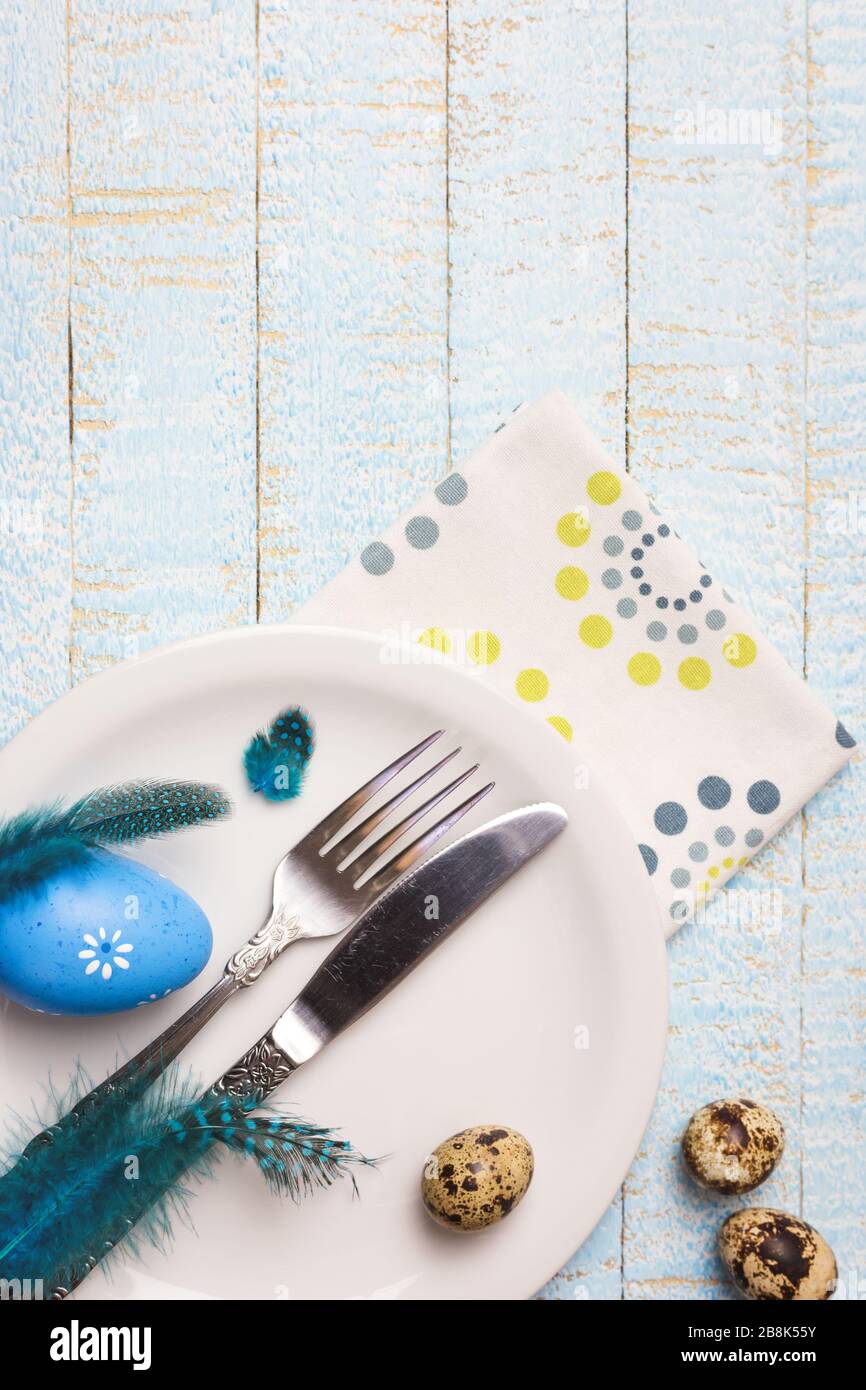 Beautiful festive or Easter table setting with eggs and feathers on light wooden background. Top view with copy space. Stock Photo