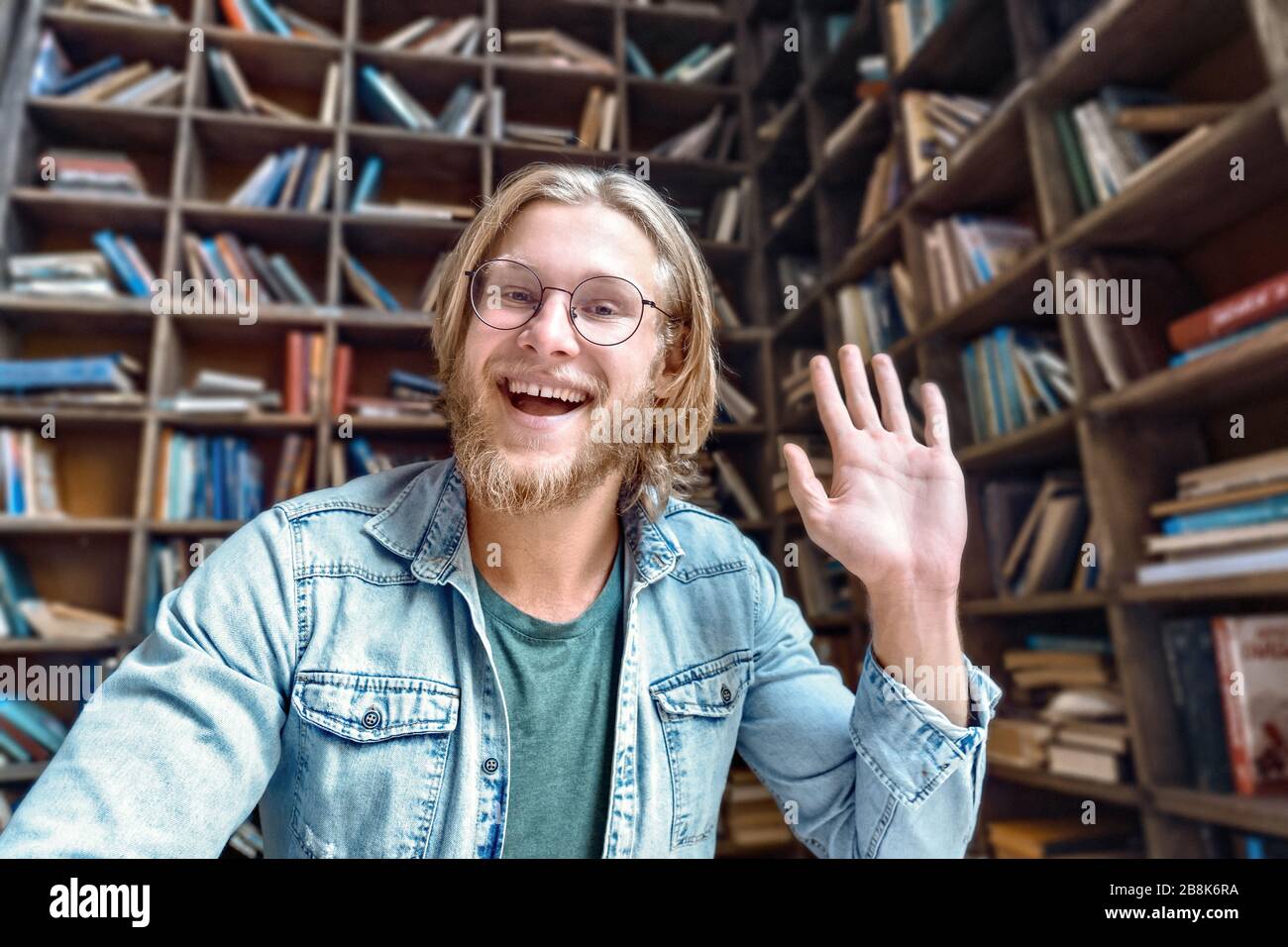 Cheerful male blogger influencer waving hand looking at camera. Stock Photo