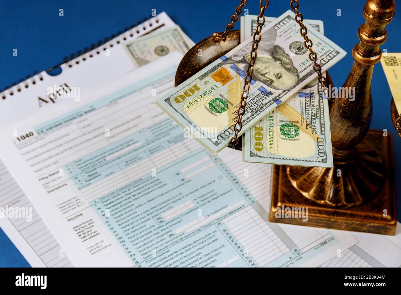 Law concept scales of justice criminal liability for non-payment of taxes of one hundred dollars bill form 1040 on U.S. Individual Income Return Tax Stock Photo