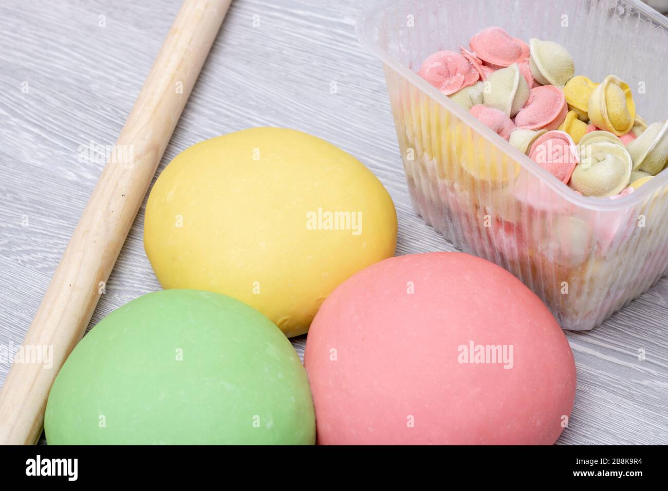 Colorful dough and pelmeni in food box, top view and copy space. Stock Photo