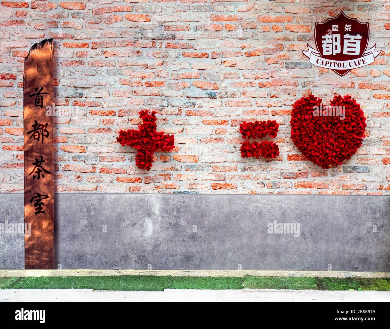 Capitol Cafe courtyard red brick wall red petals and copper signage giving homage to Chinese homage Bukit Bintang Kuala Lumpur Malaysia. Stock Photo