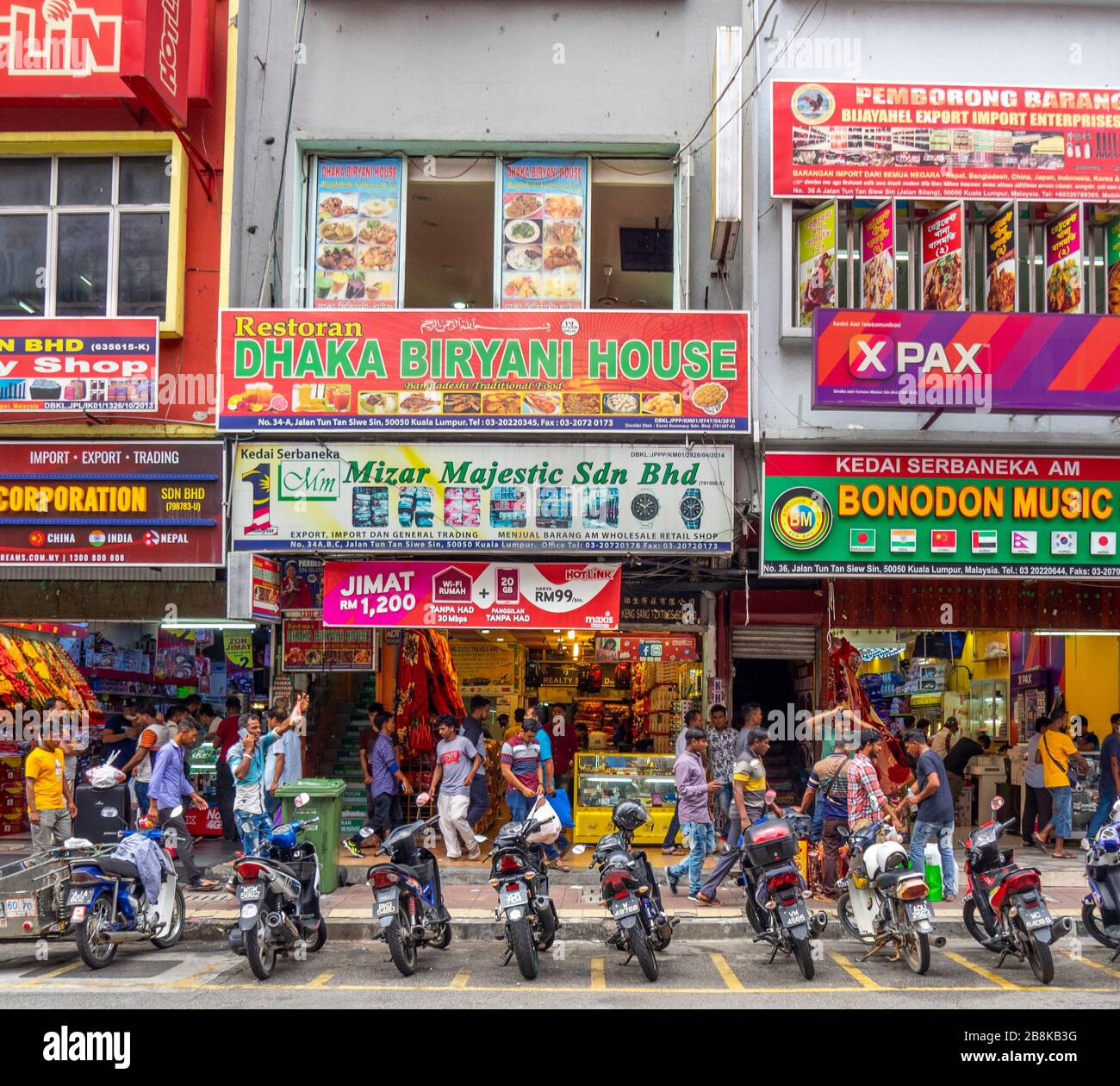 Streetscape row of shophouses parked motorcycles and Indian men walking along Jalan Tun Tan Siew Sin Chinatown Kuala Lumpur Malaysia. Stock Photo
