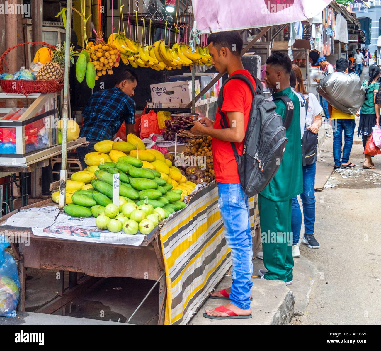 Man buying fresh fruit from a food stall in Chinatown Kuala Lumpur Malaysia. Stock Photo
