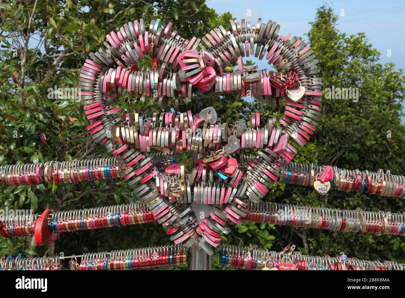 Display of romantic love padlocks, or love locks, attached to fence in the shape of a heart at the top of mountain in Langkawi, Malaysia Stock Photo
