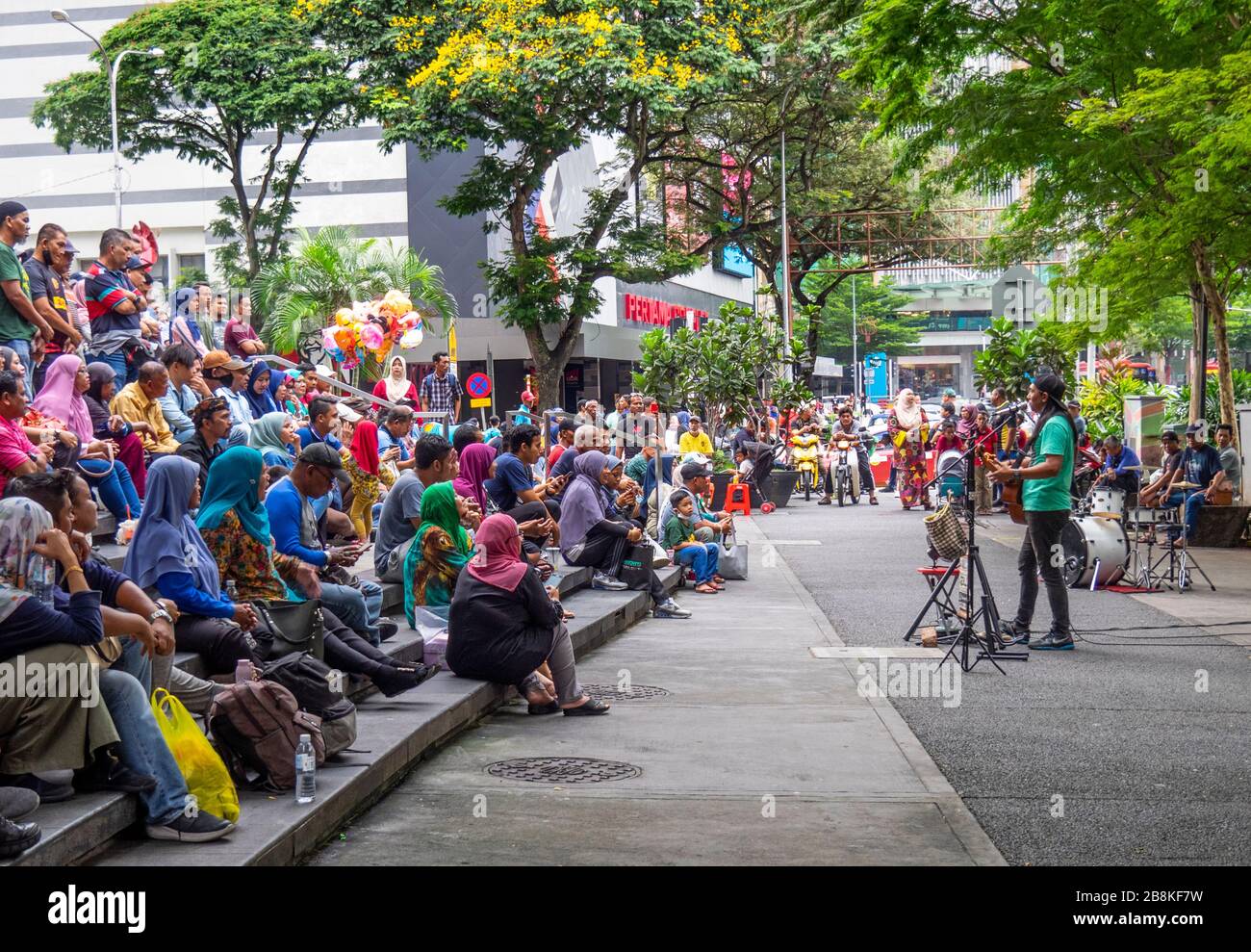 Man playing guitar free concert  street performance if front of audience in tree lined Jalan Tuanku Abdul Rahman street central Kuala Lumpur Malaysia. Stock Photo