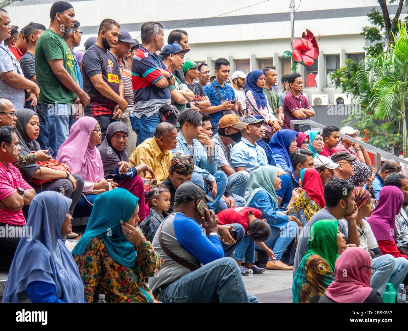 Crowd sitting on steps watching free concert in  tree lined Jalan Tuanku Abdul Rahman street central Kuala Lumpur Malaysia. Stock Photo