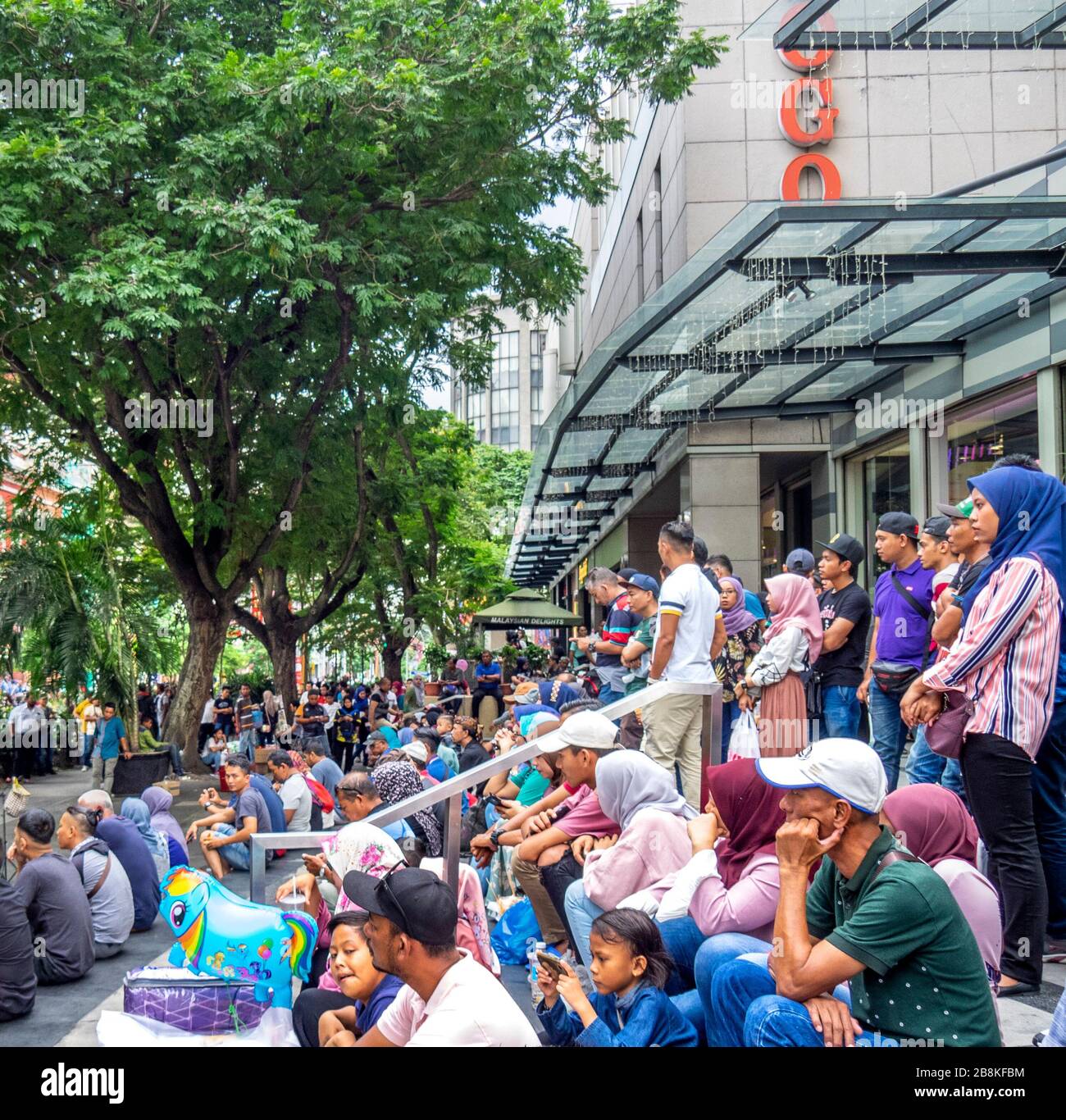 Crowd sitting on steps watching free concert in  tree lined Jalan Tuanku Abdul Rahman street central Kuala Lumpur Malaysia. Stock Photo