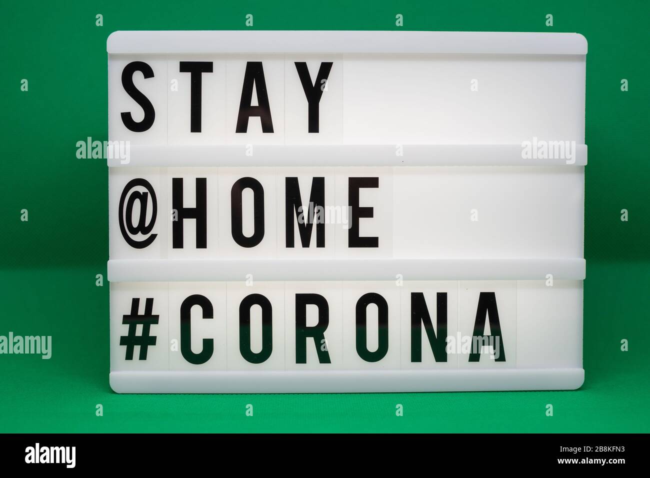 is written on an illuminated panel with black letters: Stay at home #Corona Stock Photo