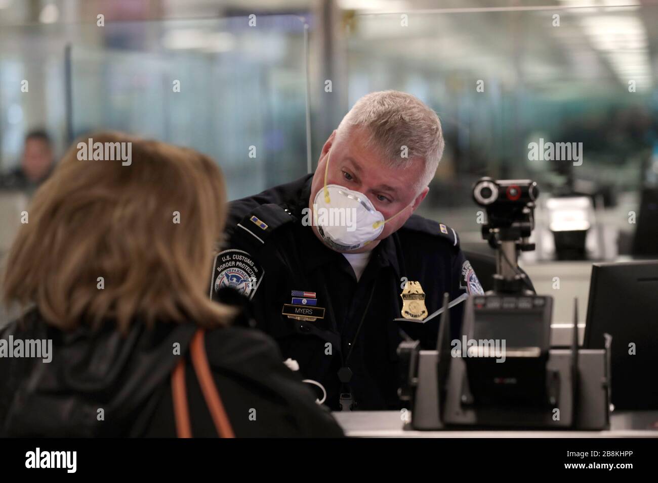 U.S. Customs and Border Protection officers screen international passengers arriving at Dulles International Airport wearing personal protective equipment March 13, 2020 in Dulles, Virginia. In response to the COVID-19, coronavirus pandemic CBP officers and travelers have begun wearing gloves and masks as protection from viral exposure. Stock Photo