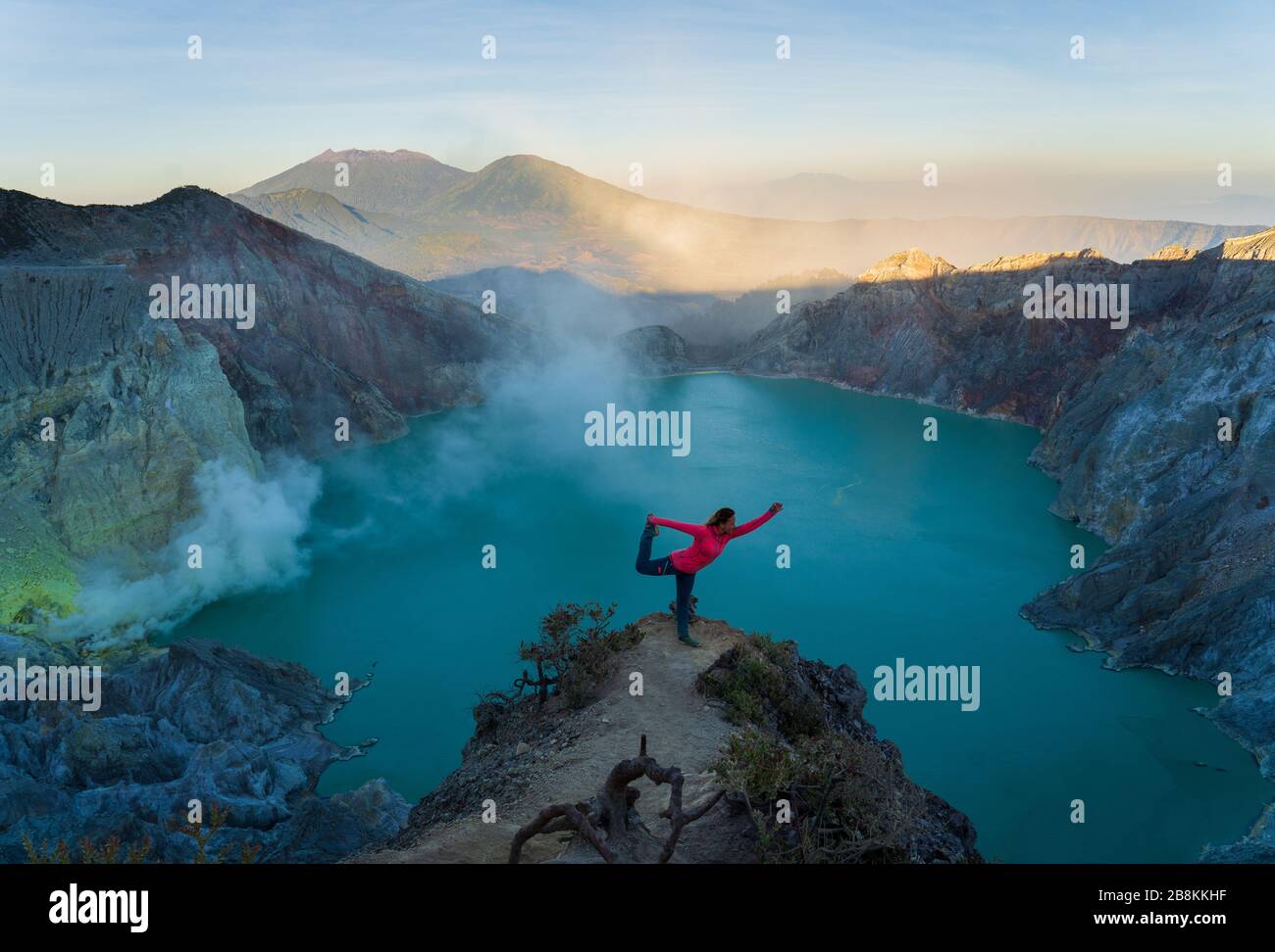 Yoga pose at a more exotic location in comparison to a gym or a studio. A brave person doing a yoga pose at Ijen Crater, Indonesia. Stock Photo