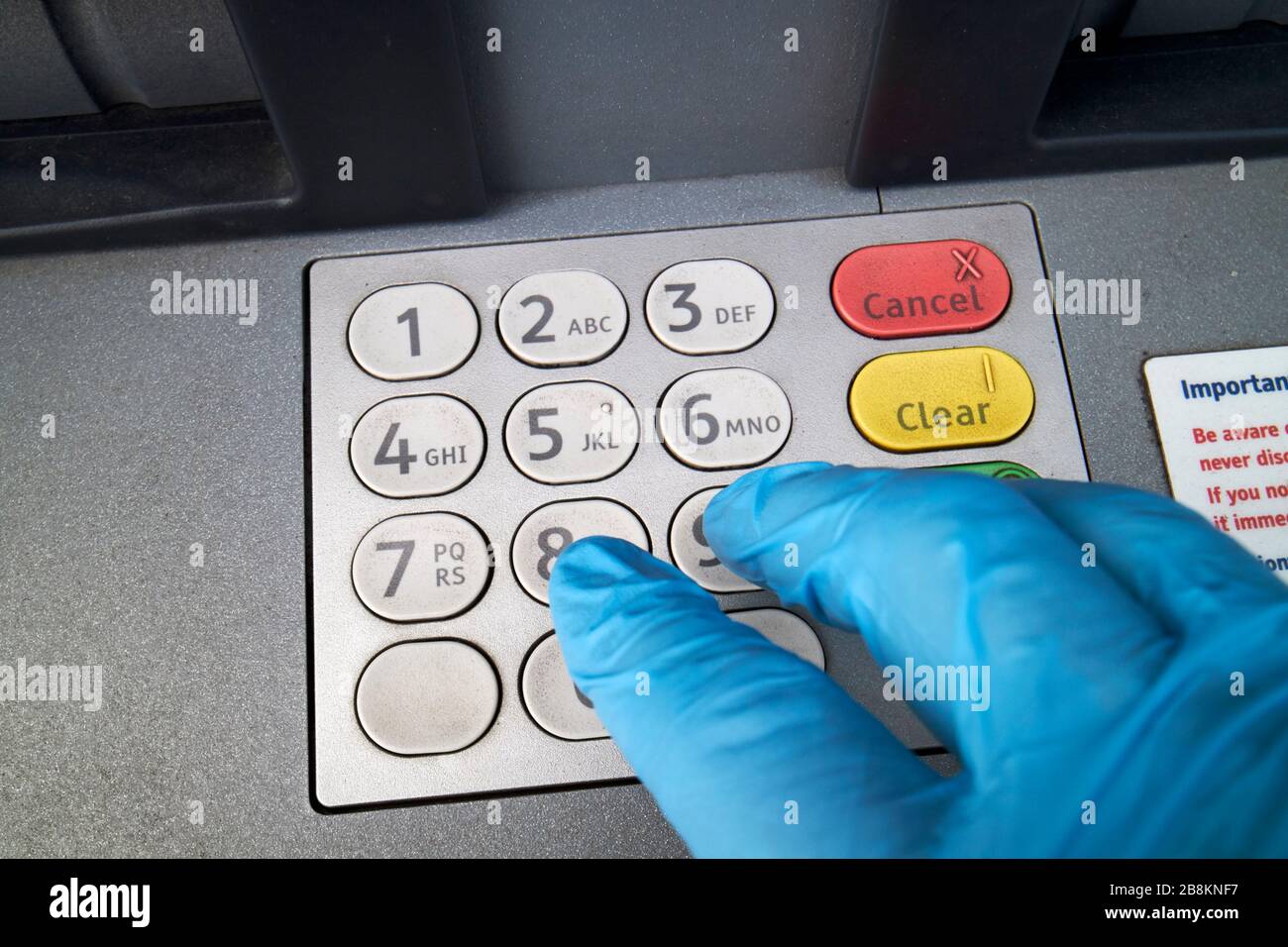 using gloved hand on dirty cash machine keypad due to covid-19 precautions glengormley newtownabbey northern ireland uk Stock Photo