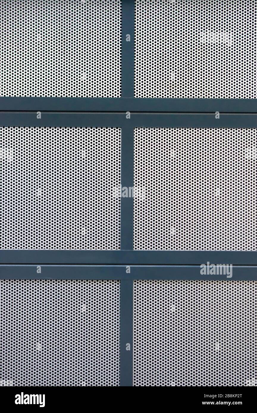 Section of a cover made of several plates of silver perforated plate, which are bordered with blue painted metal profiles Stock Photo