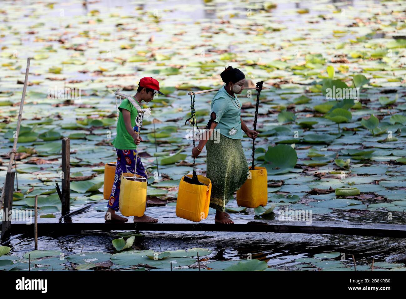 Yangon, Myanmar. 22nd Mar, 2020. Residents carry water from a lake at Dala Township on the outskirts of Yangon, Myanmar, March 22, 2020. World Water Day is observed annually on March 22. Credit: U Aung/Xinhua/Alamy Live News Stock Photo