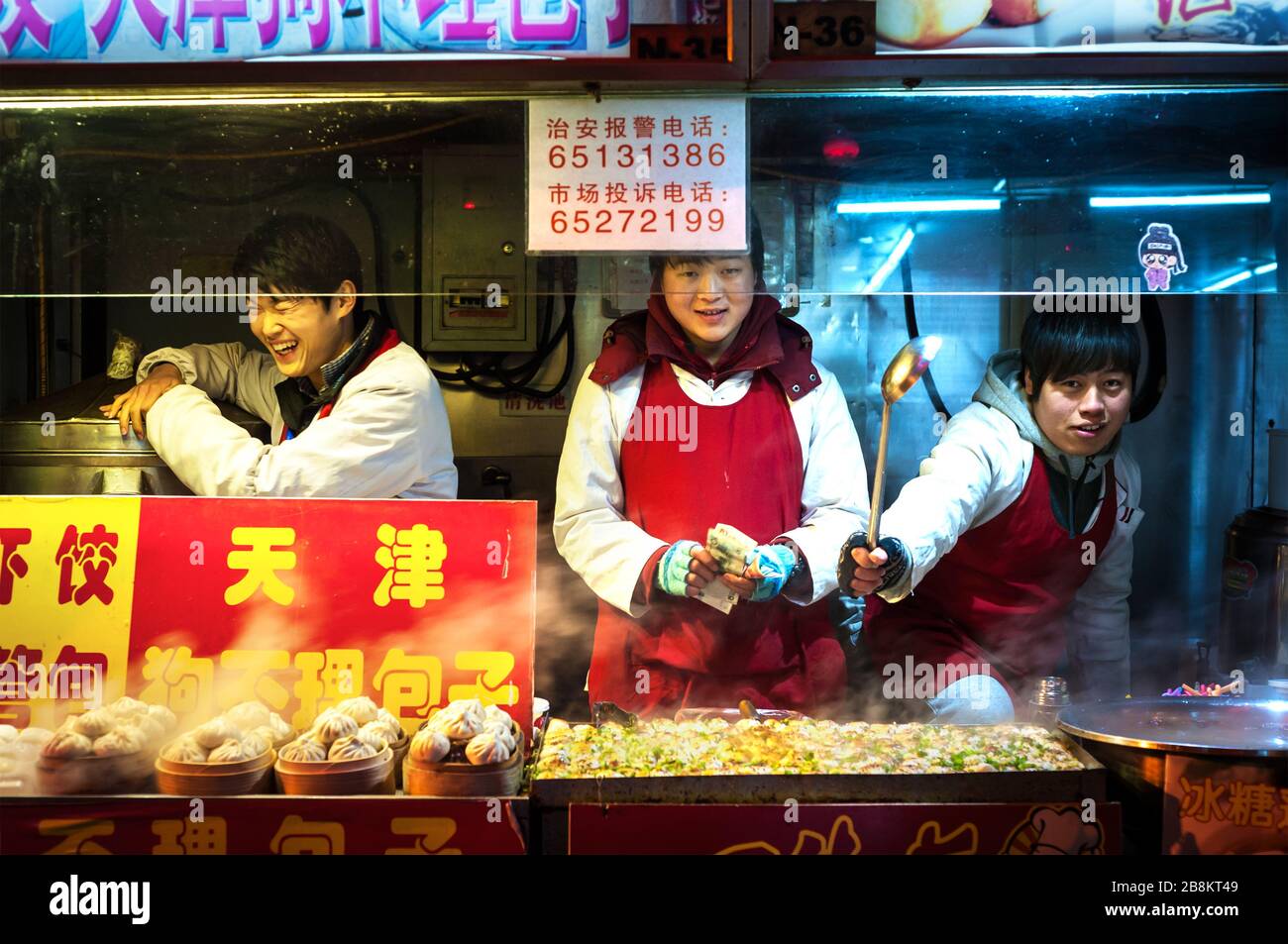 WANGFUJING NIGHT MARKET, BEIJING - DEC 25, 2013 - Young snack vendors enjoying themselves at Wangfujing snack street, Beijing Stock Photo