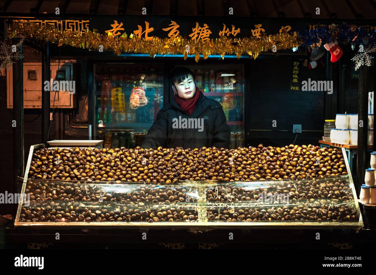 WANGFUJING NIGHT MARKET, BEIJING - DEC 25, 2013 - Young chestnut seller at Wangfujing snack street, Beijing Stock Photo