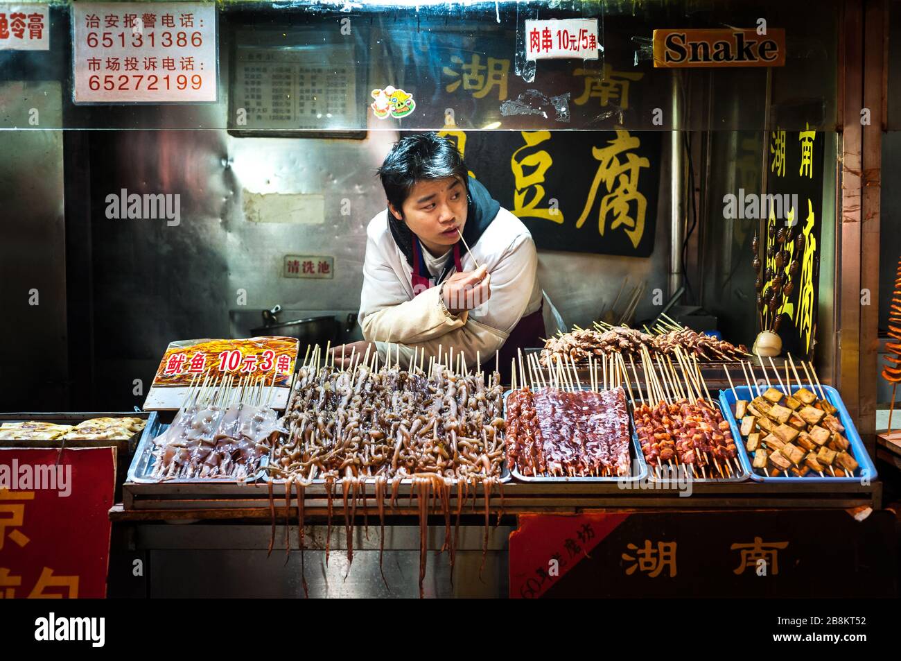WANGFUJING NIGHT MARKET, BEIJING - DEC 25, 2013 - Young snack vendor at Wangfujing snack street, Beijing Stock Photo