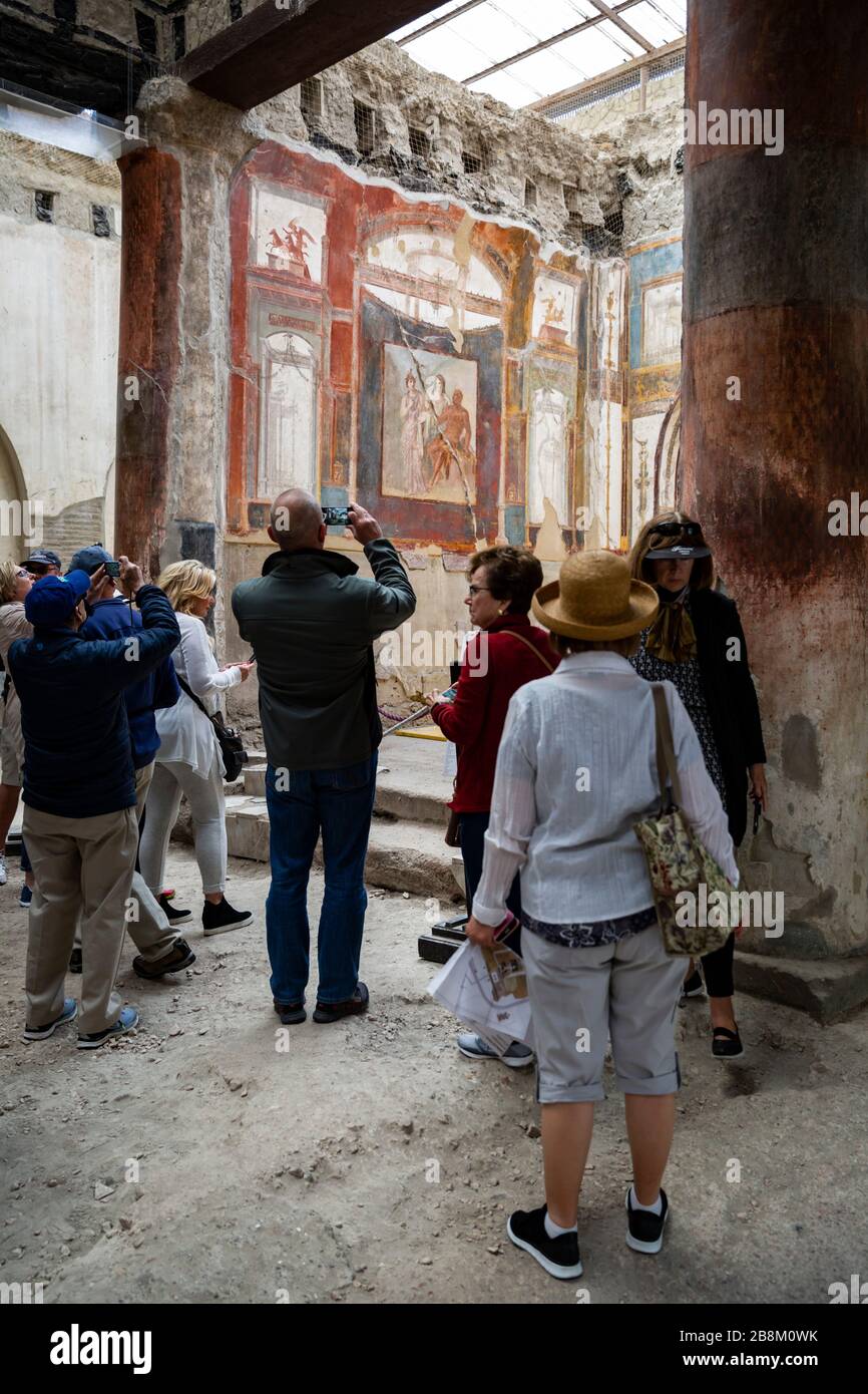 A group of tourists viewing ancient Roman frescos, Herculaneum, Campania, Italy. Stock Photo