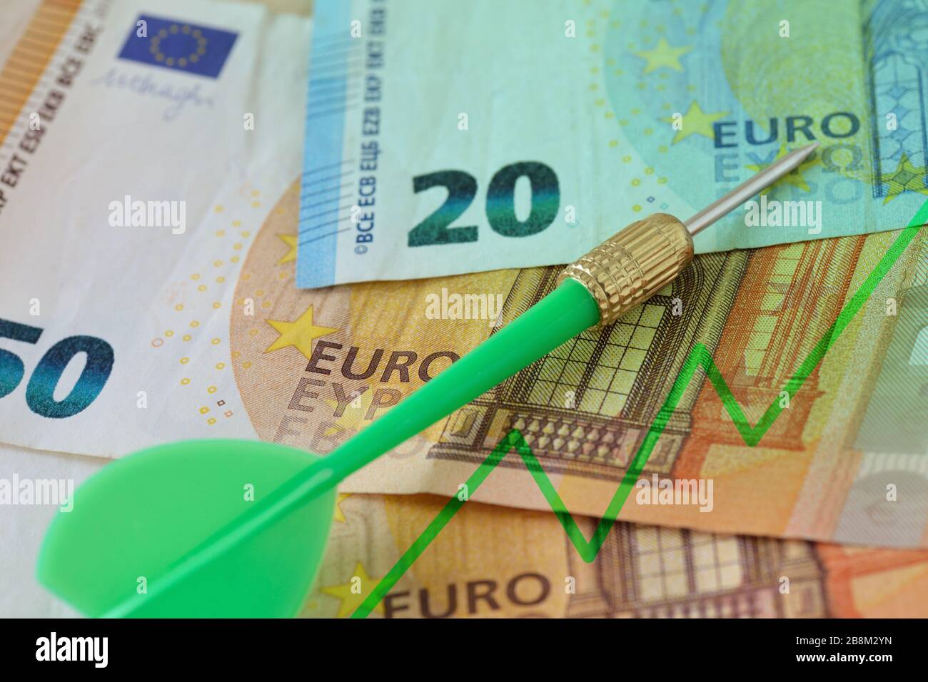Green dart and graphic with ascending line on euro banknotes - Concept of increasing money value Stock Photo