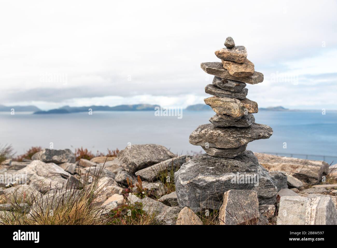 Stack of stones balancing on top of each other. Ocean and clouds in background. Rocks on the ground. Stock Photo
