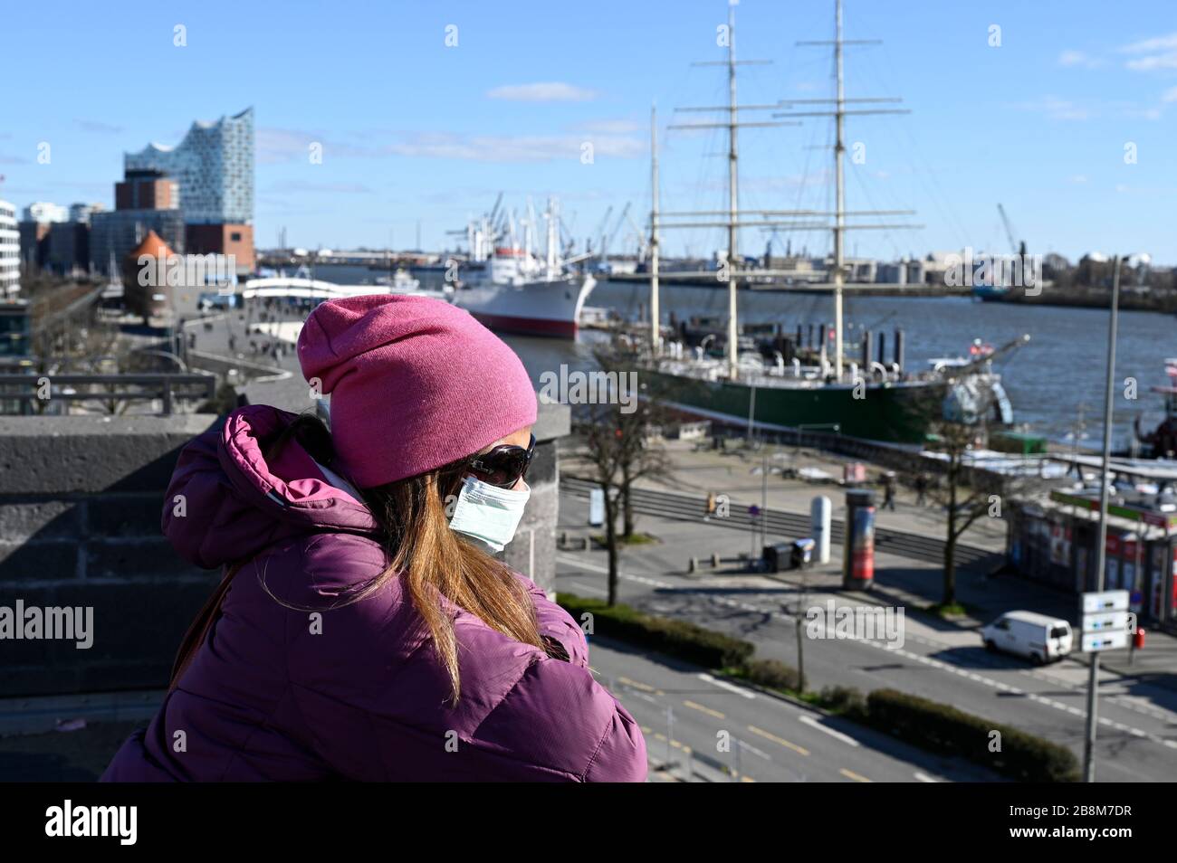 GERMANY, Hamburg, Corona Virus, COVID-19 , empty streets at river Elbe and Landungsbrücken, behind concert hall Elbphilharmonie, woman with protective mask, respirator mask Stock Photo