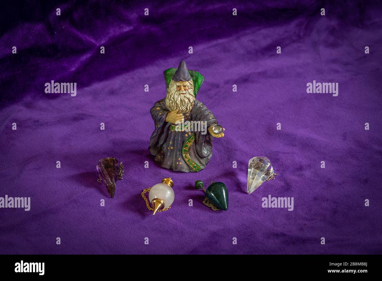 Fortune telling: small wizzard figure and four crystal dowsing pendulums Stock Photo