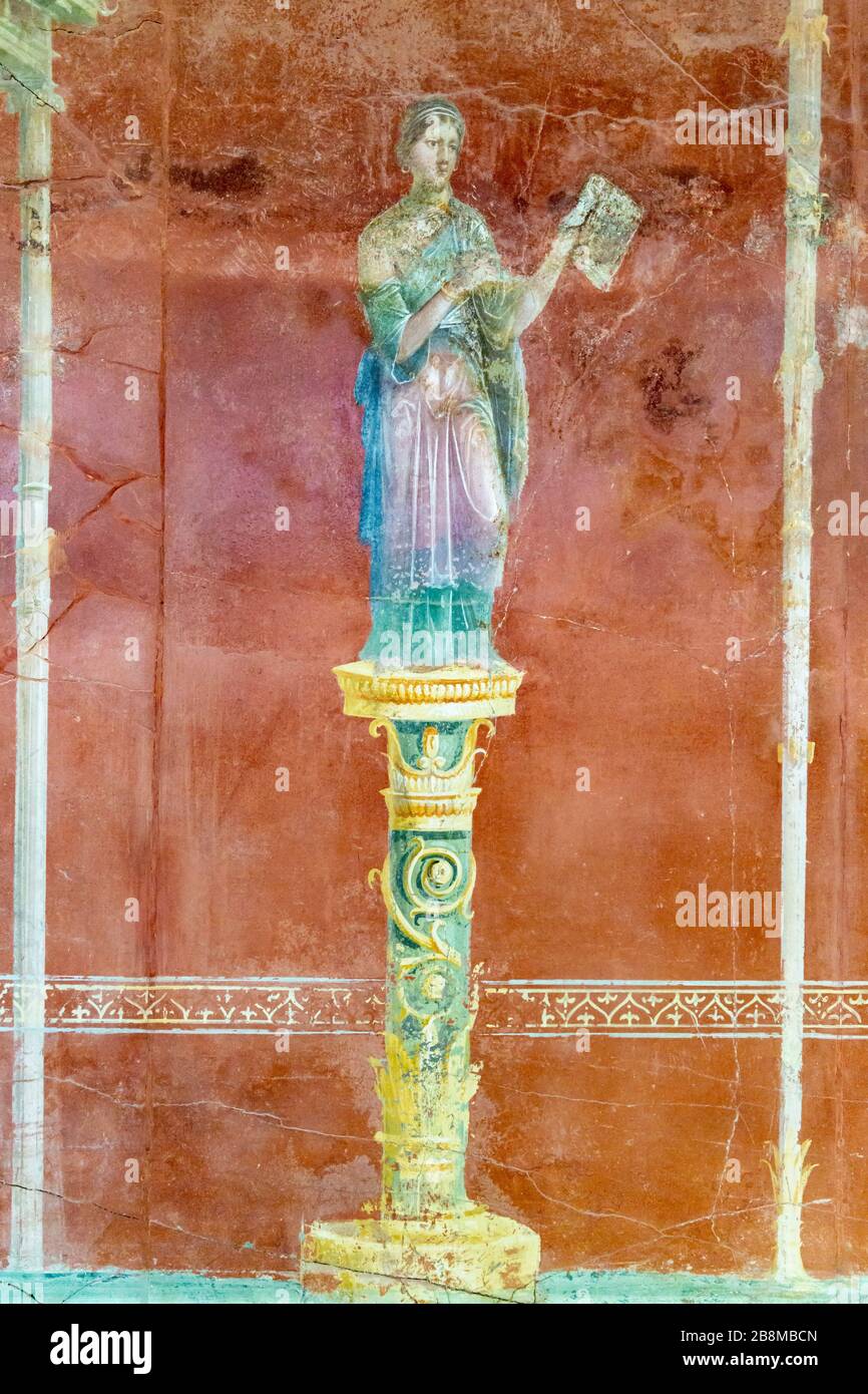Ancient painted wall fresco of a woman standing on a pedestal, Pompeii, Campania, Italy. Stock Photo