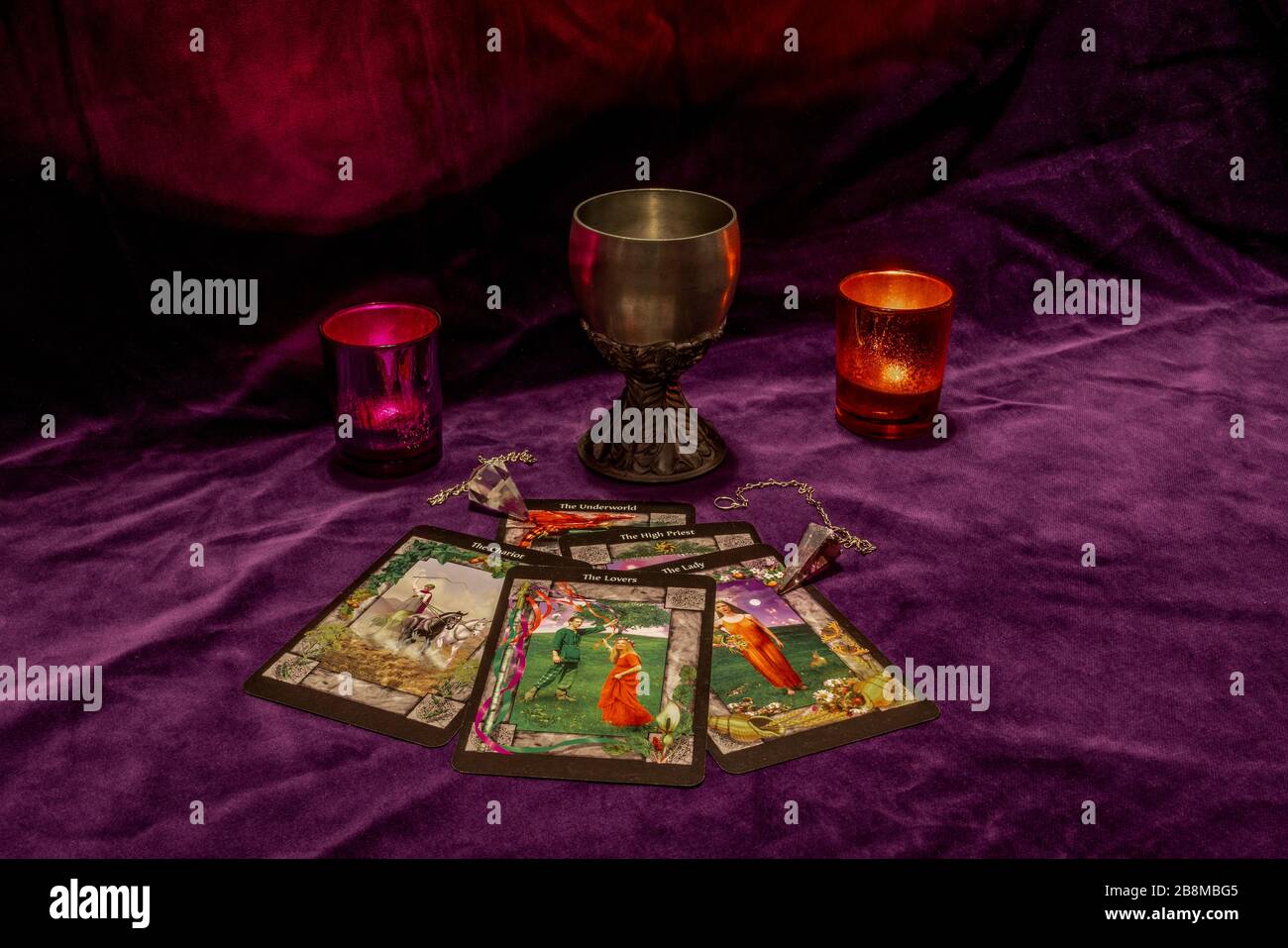 Fortune telling with tarot cards, crystal dowsing pendulums, a tin chalice and candles Stock Photo