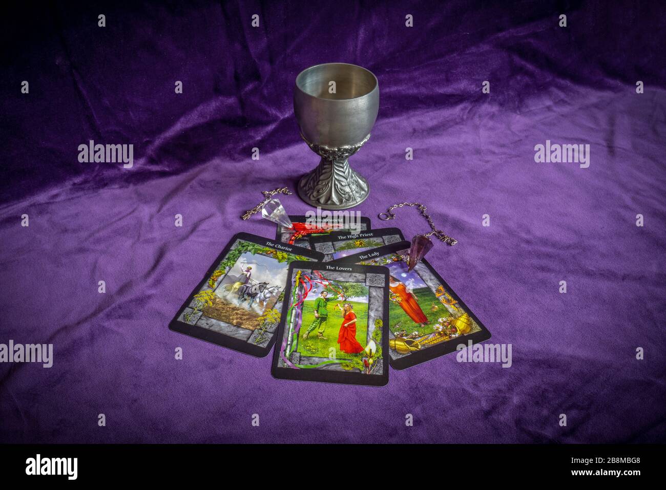 Fortune telling with tarot cards, crystal dowsing pendulums and a tin chalice Stock Photo