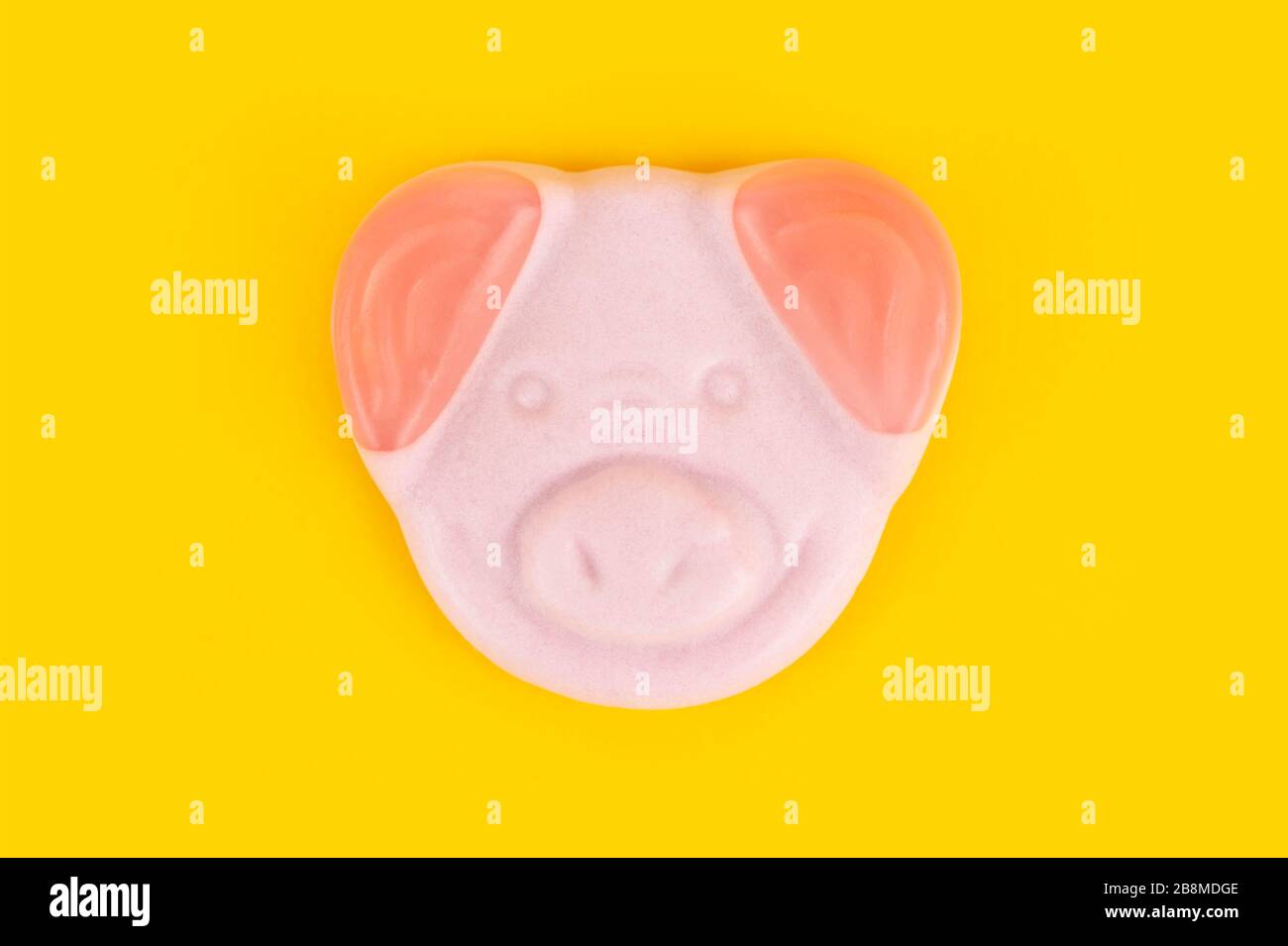 An M&S Percy Pig sweet shot on a yellow background. Stock Photo