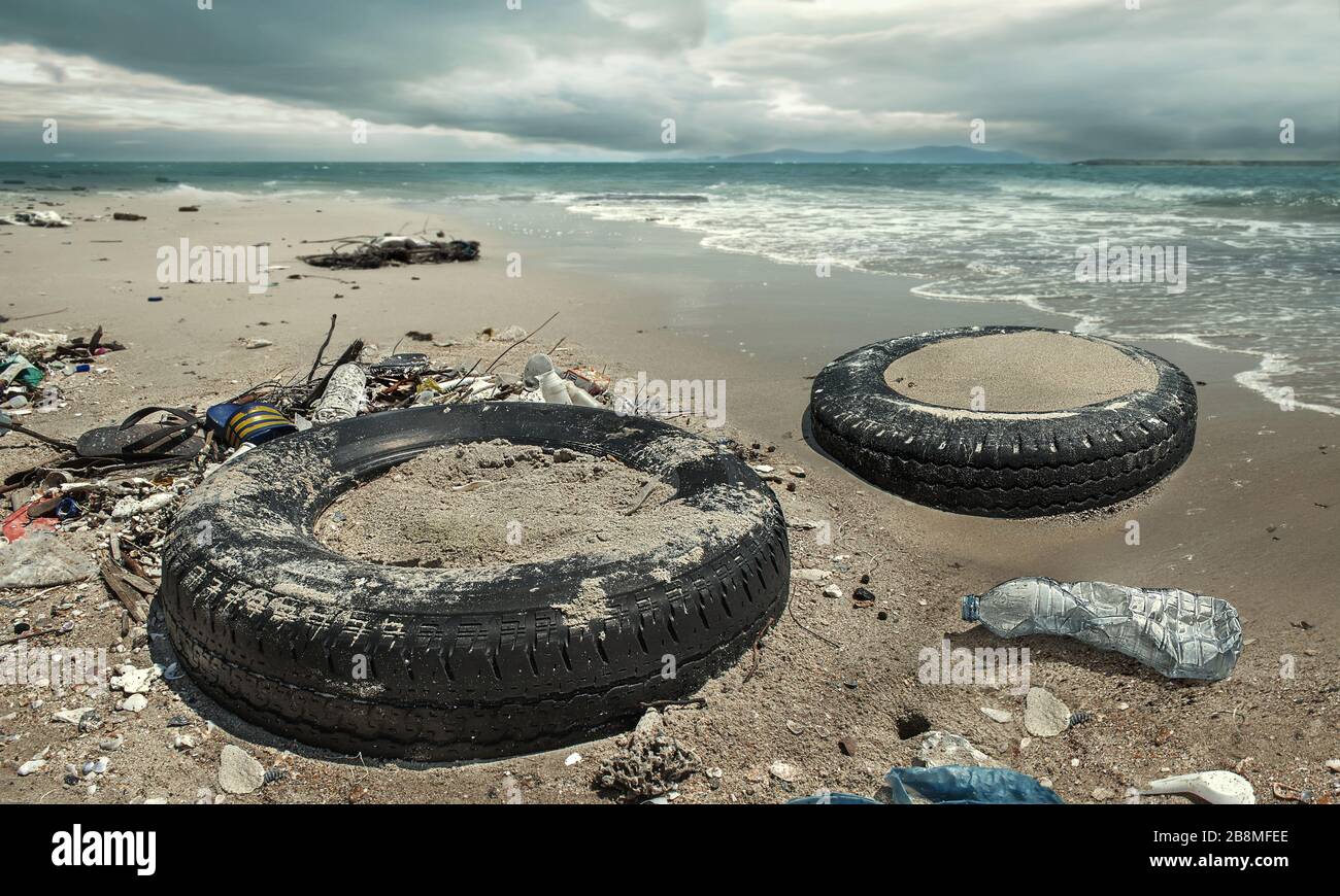 Car tire and plastic bottles pollution in muddy puddle on beach. (Environment concept) Stock Photo