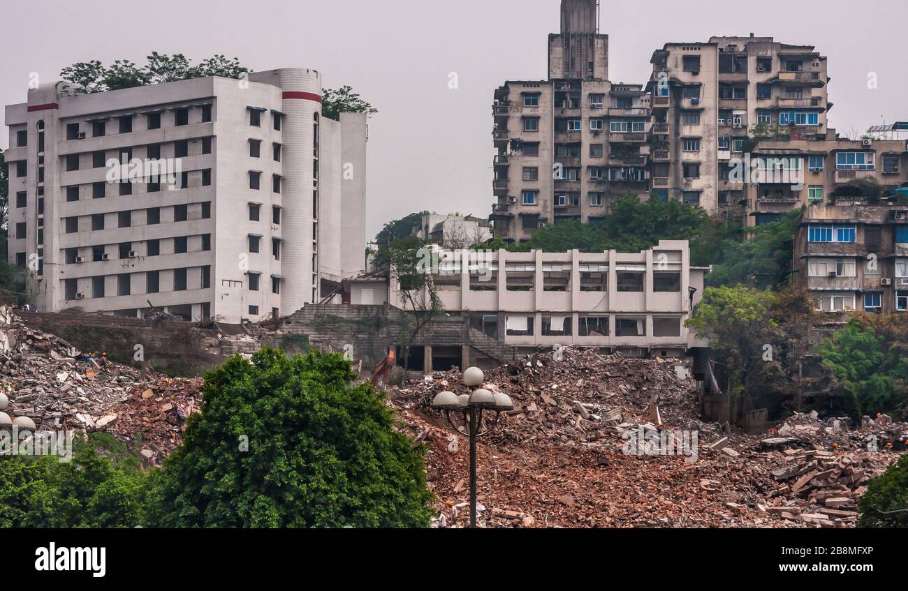 Chongqing, China - May 9, 2010: Downtown, off Peoples Square. Huge demolition rubble site with old and newer buildings in back and some green foliage. Stock Photo