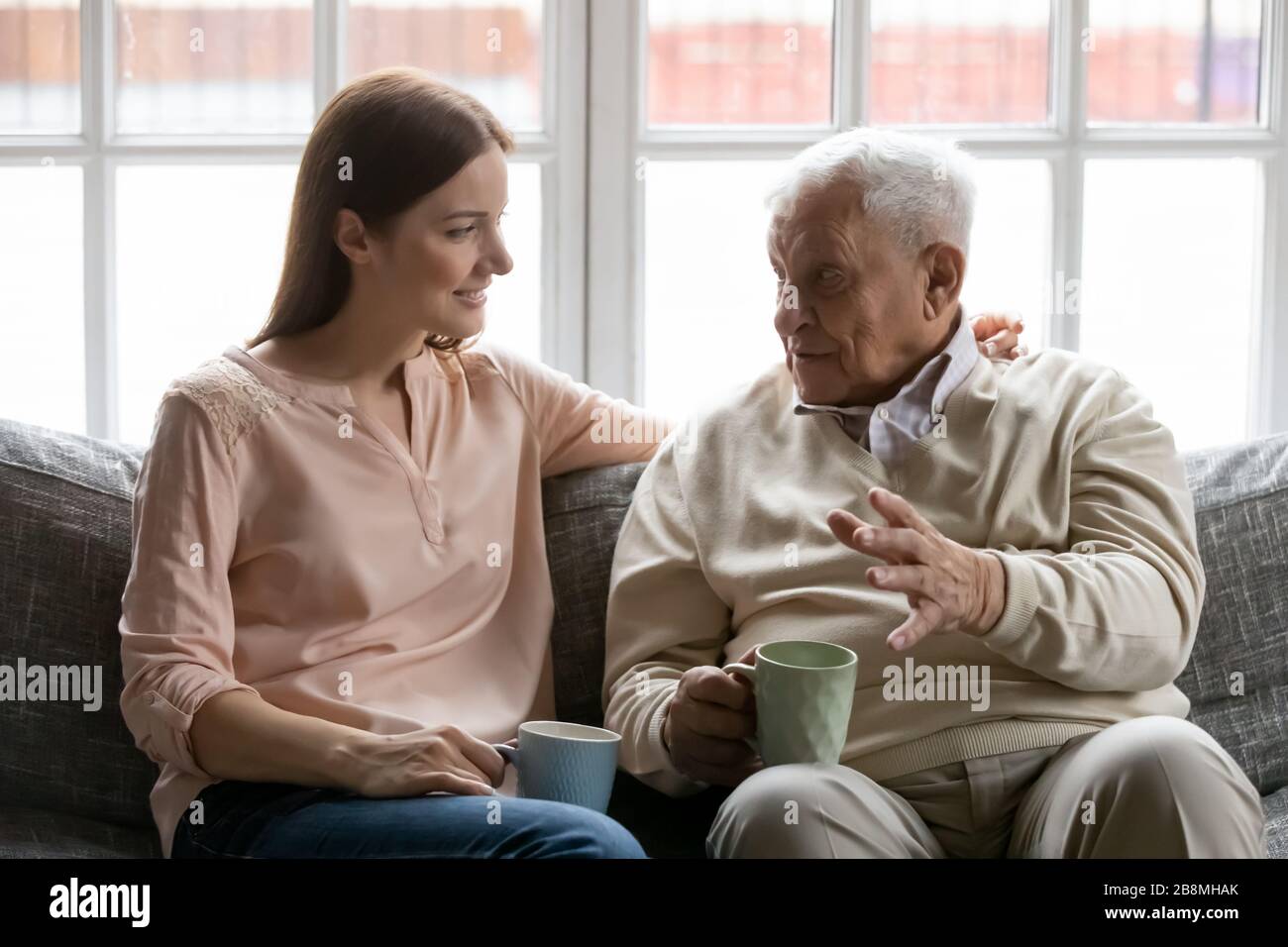 Adult daughter listens to aged father during teatime at home Stock Photo