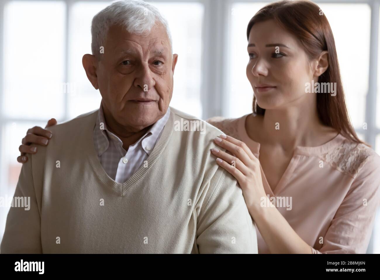 Caring grownup granddaughter express sympathy stroking elderly grandfather Stock Photo