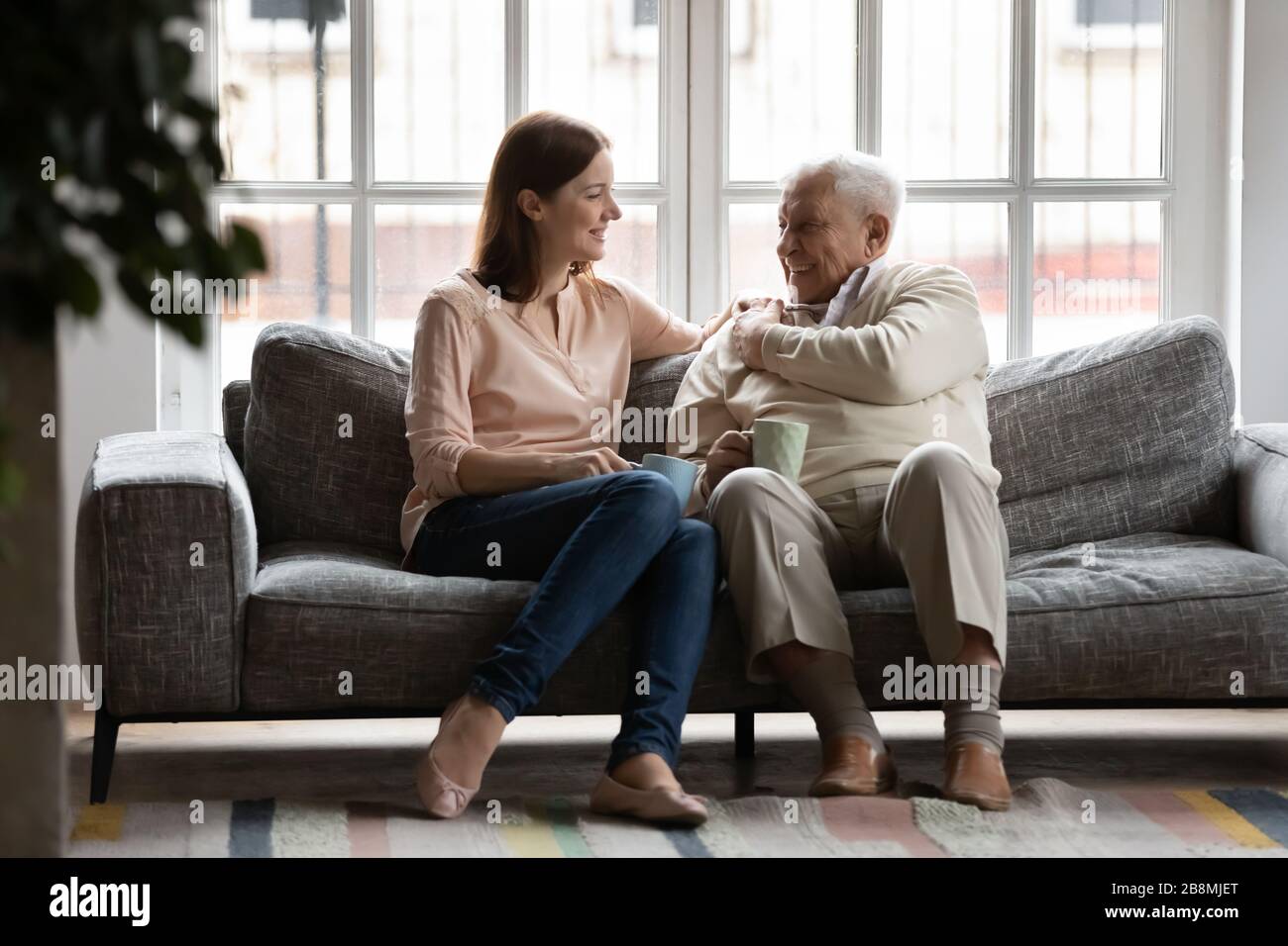 Caring adult daughter talking drinking tea with old father Stock Photo