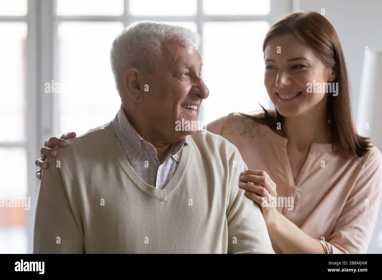 Happy old grandfather and adult granddaughter communicating at home Stock Photo