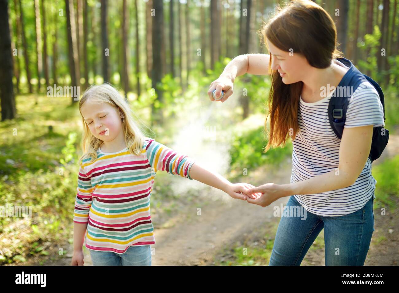 Mother applying insect repellent to her daughter before forest hike beautiful summer day. Protecting children from biting insects at summer. Using bug Stock Photo