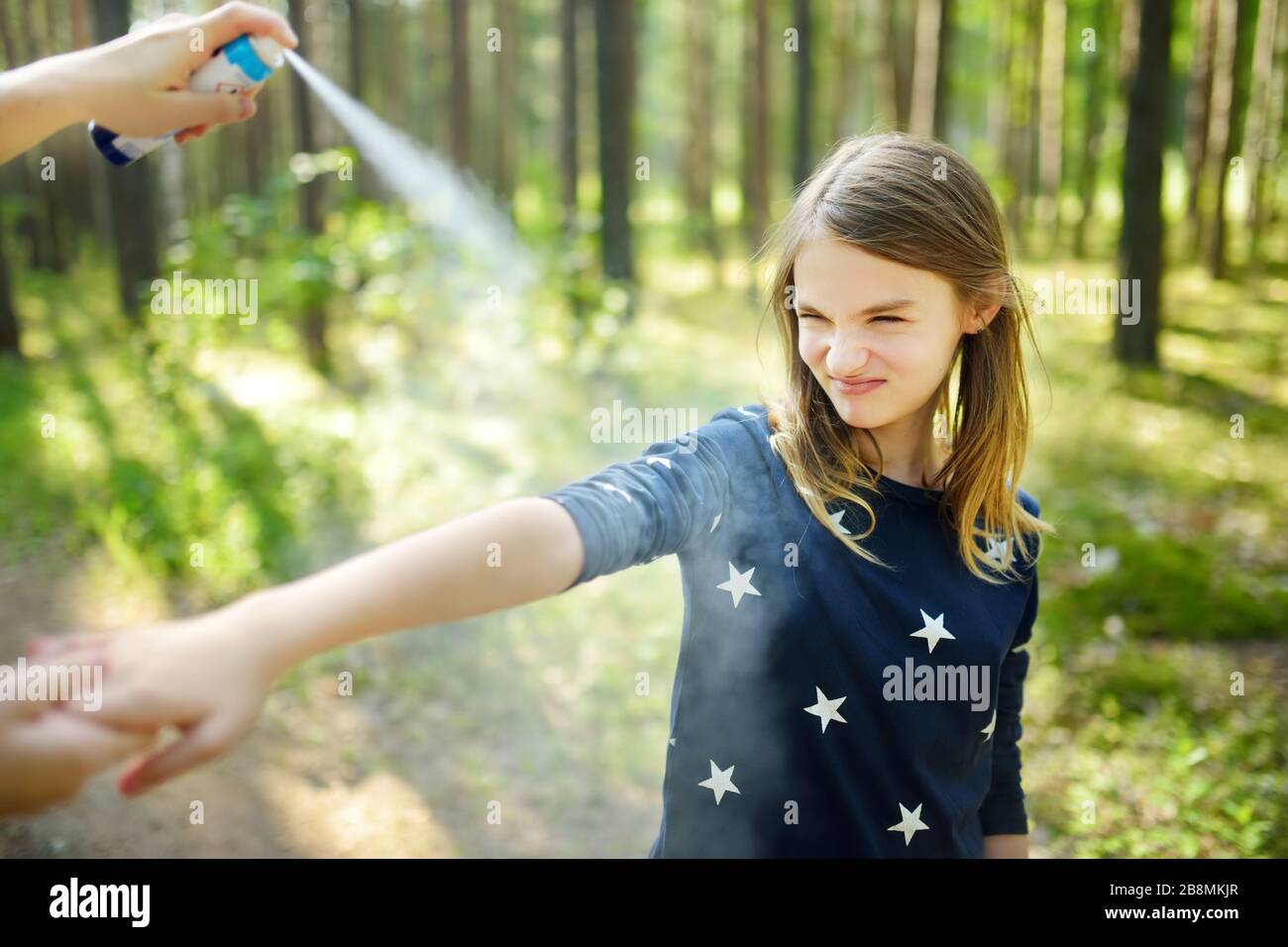 Mother applying insect repellent to her daughter before forest hike beautiful summer day. Protecting children from biting insects at summer. Using bug Stock Photo