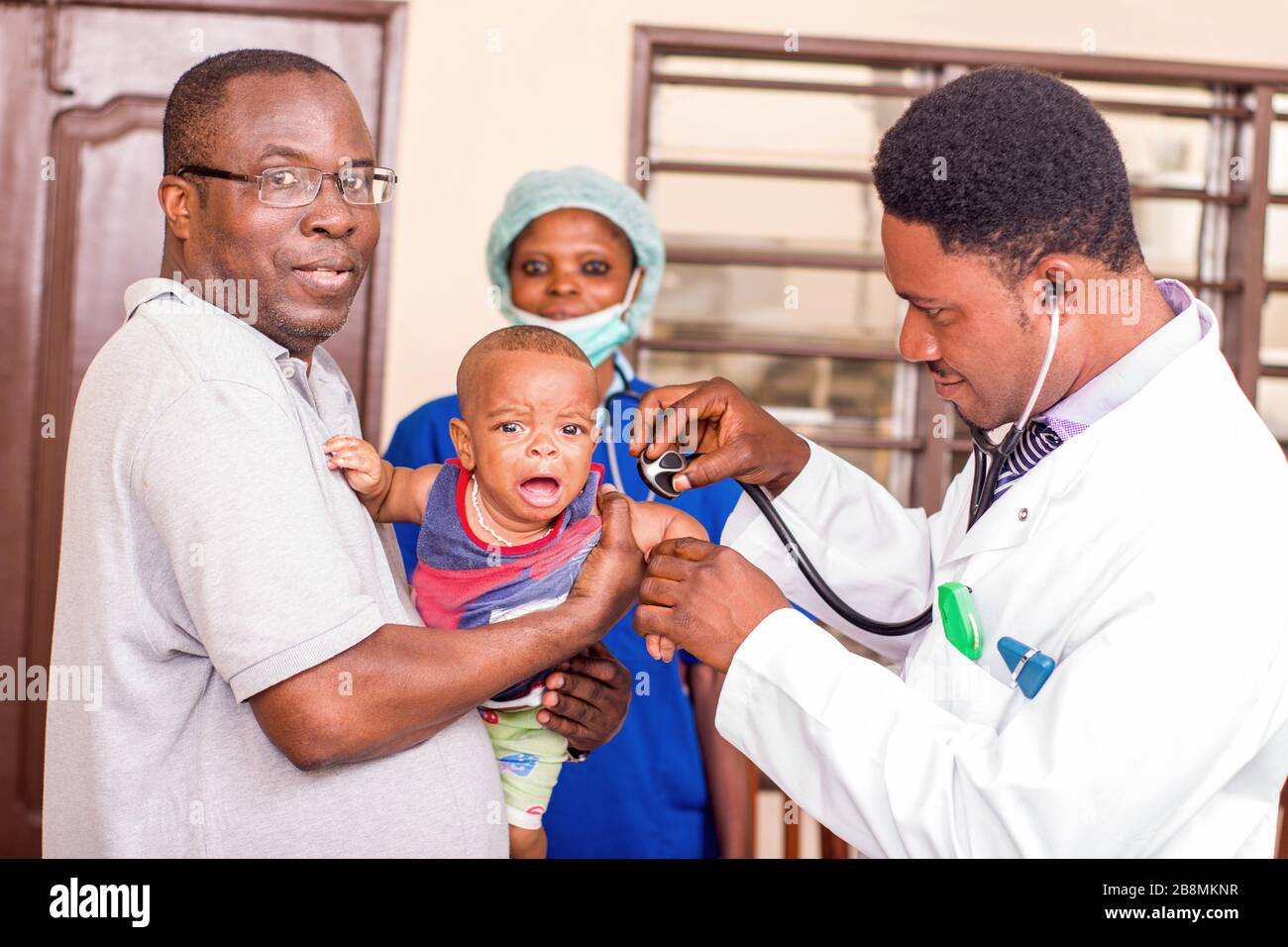 a young man catches his baby during the doctor examines him at the hospital. Stock Photo