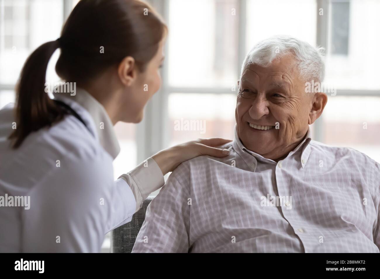 Caring geriatric nurse in white coat cares for elderly man Stock Photo