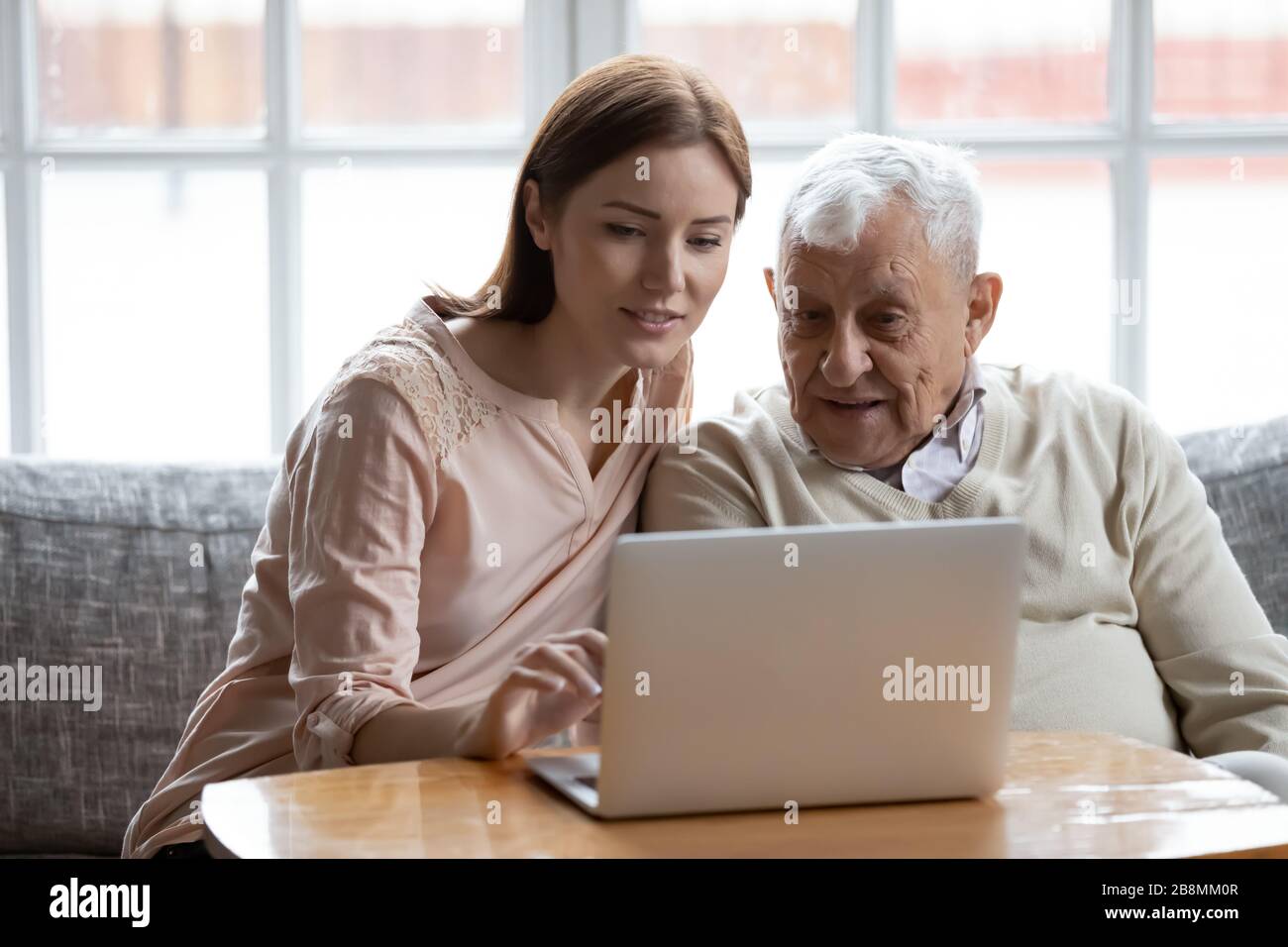 Adult daughter old father choose services via internet using computer Stock Photo