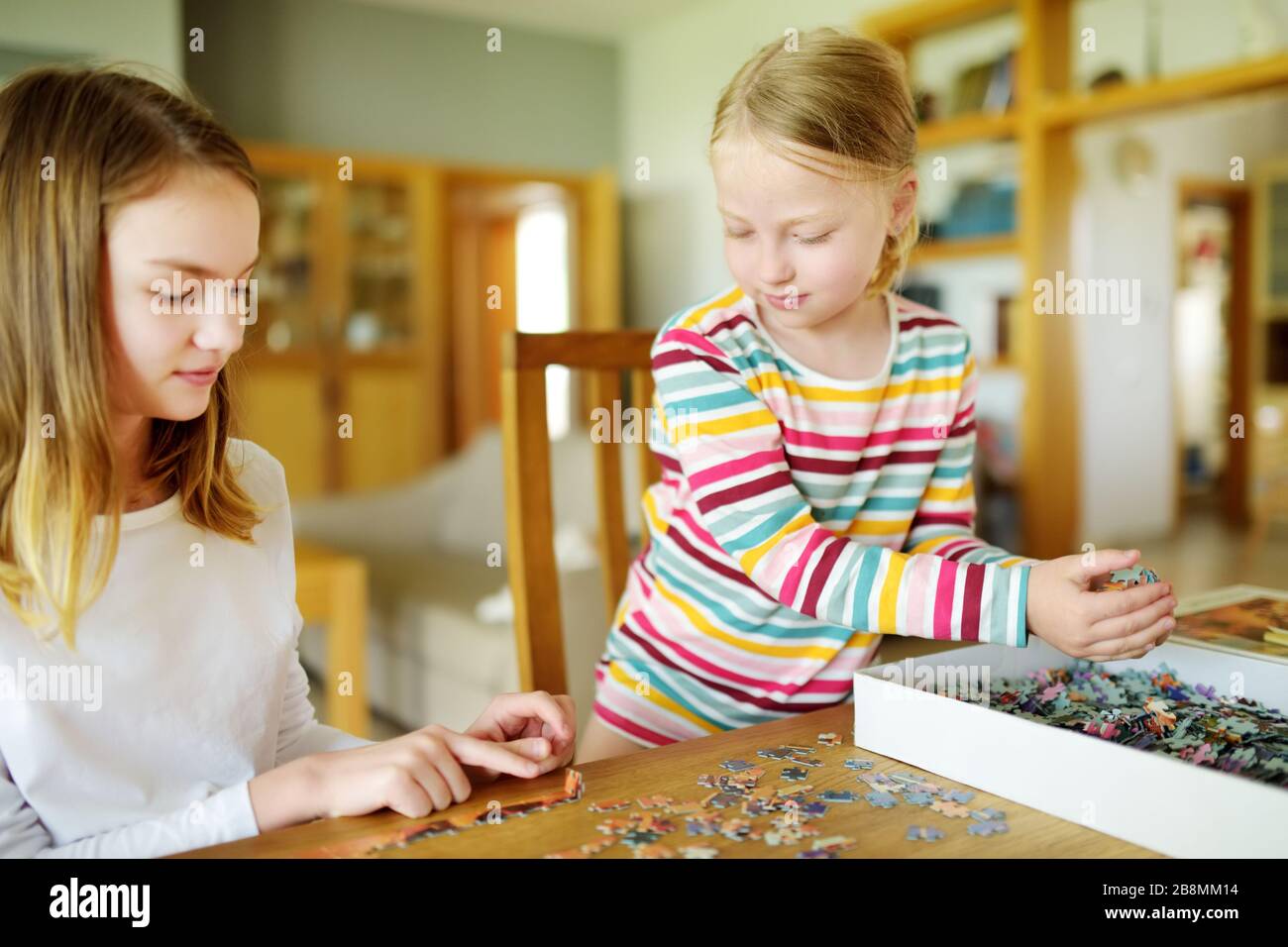 Cute young girls playing puzzles at home. Children connecting jigsaw