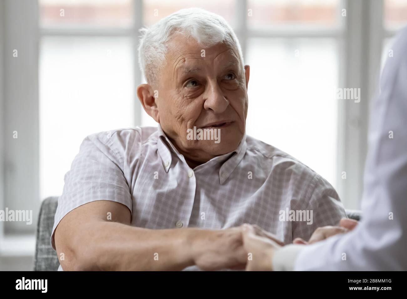Woman nurse holding hands of elderly man showing care Stock Photo