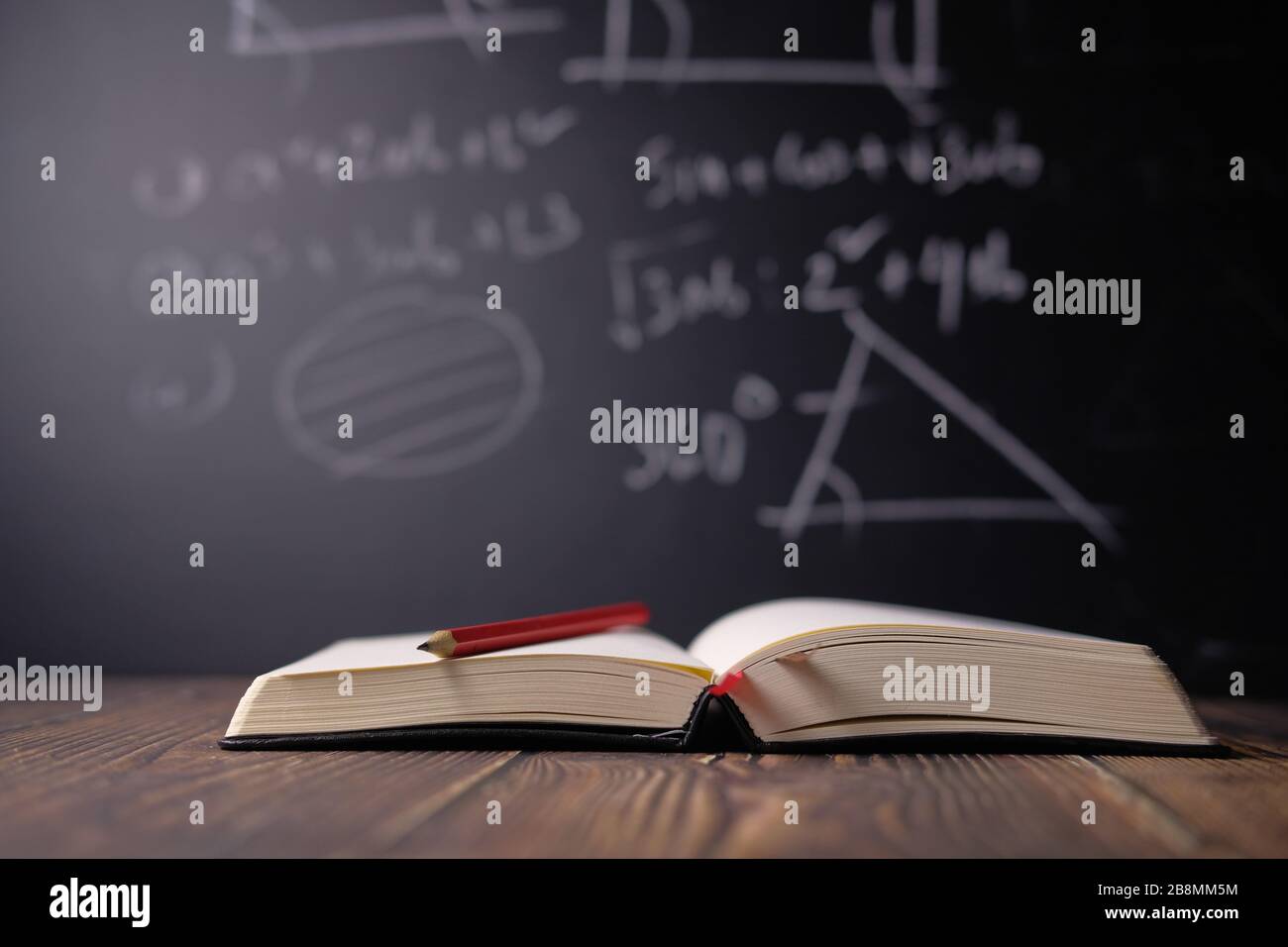 Open books on the table against black board. Stock Photo