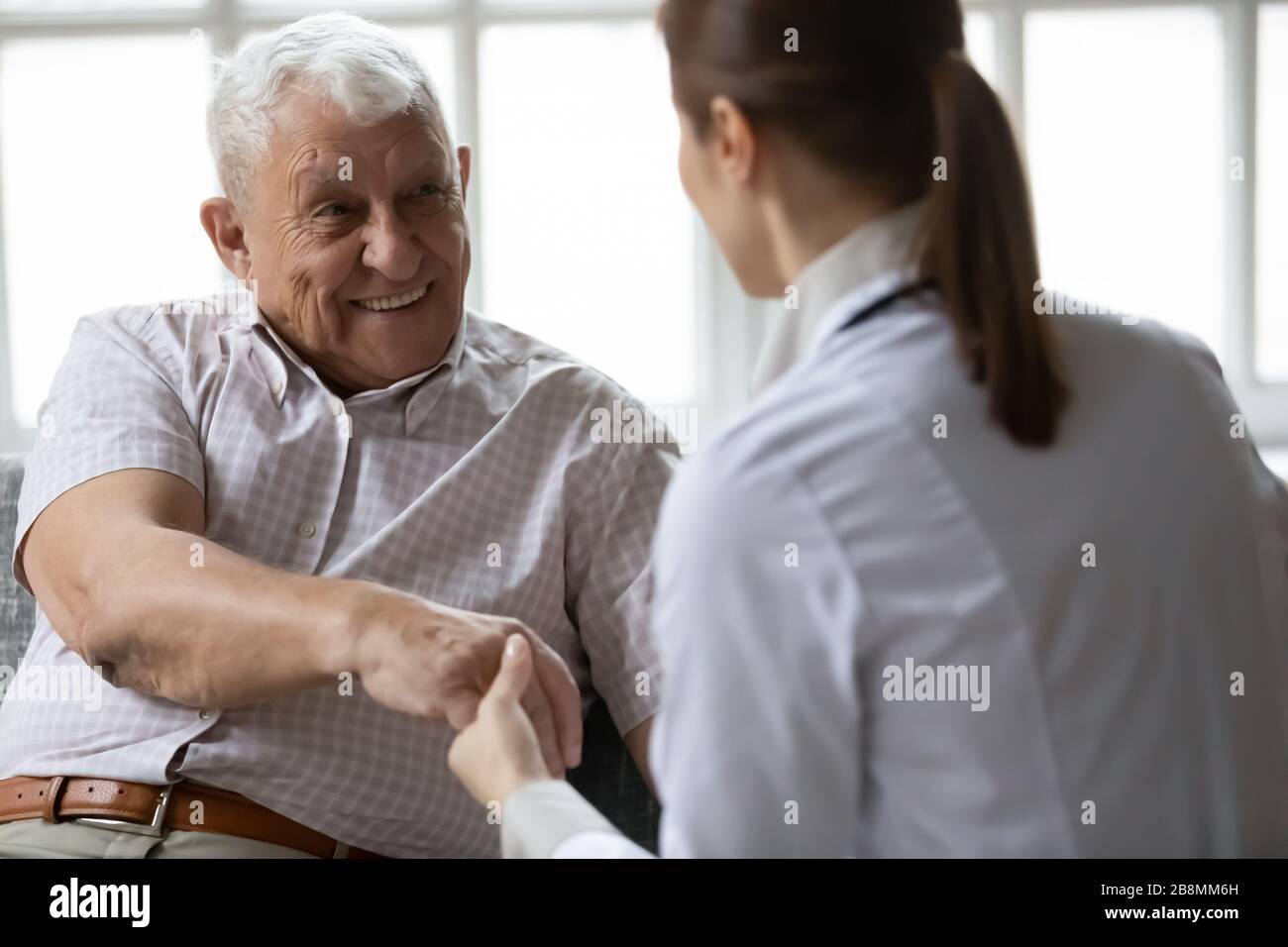 Nurse in uniform talking during day visit to elderly patient Stock Photo