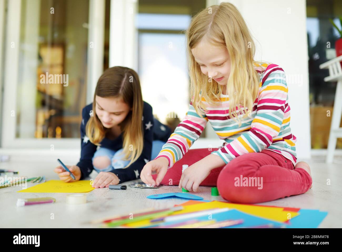 Two young sisters drawing with colorful pencils at home. Creative kids ...